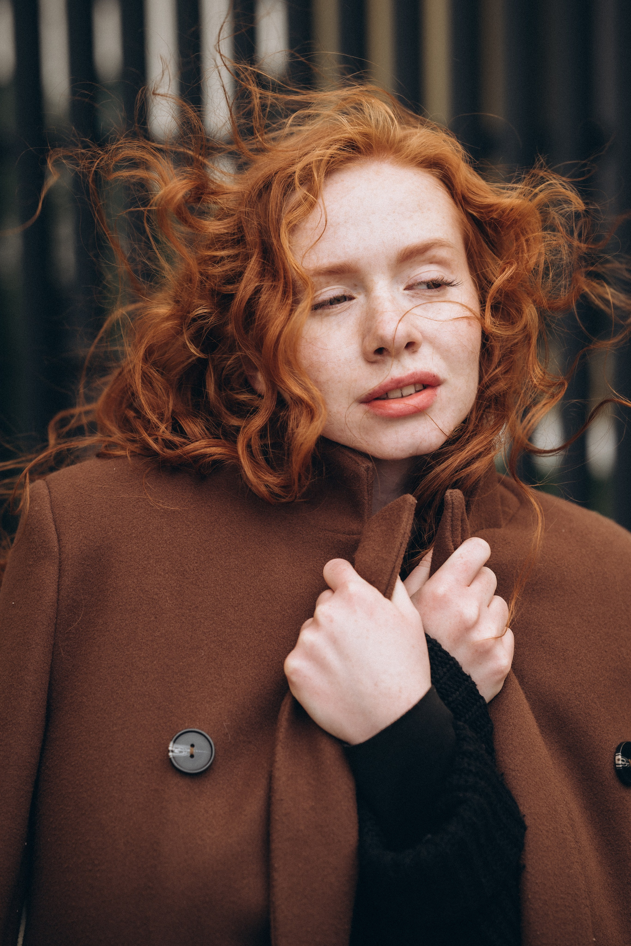 фотосессия девушки на улице в москве — девушка укуталась в пальто и её волосы развиваются на ветру