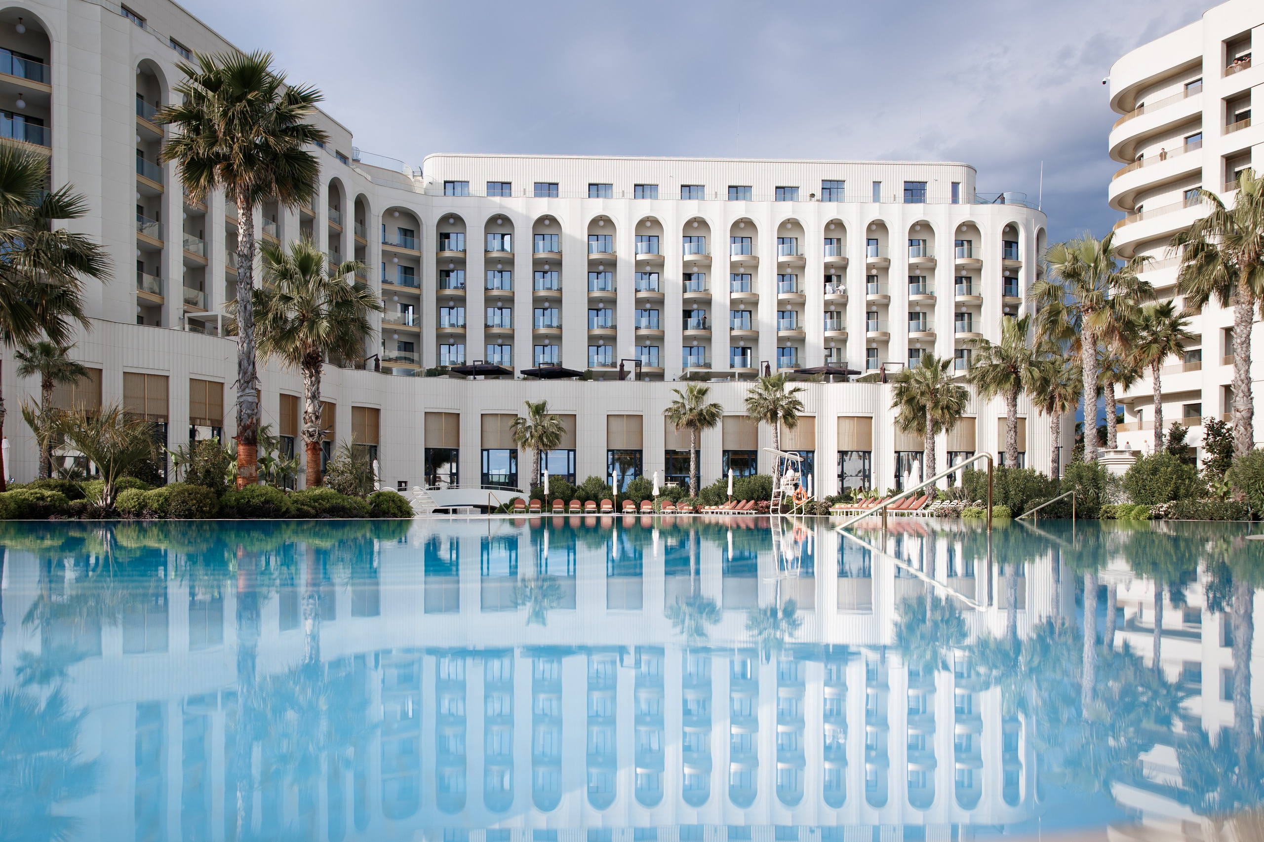 Релакс-зона: Лазурная вода открытого бассейна отеля Mantera, окруженного пальмами и современной архитектурой.