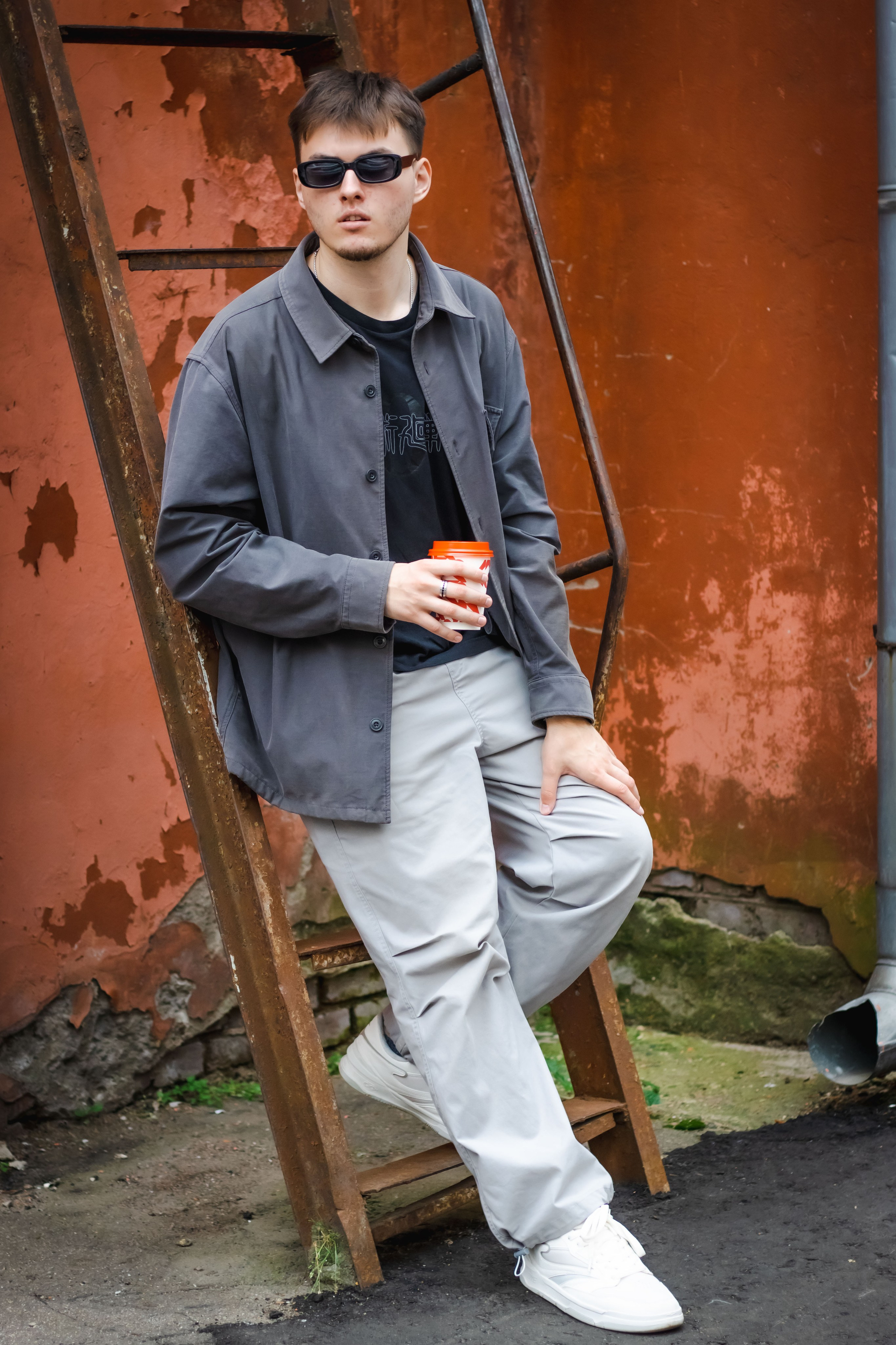 парень пьет кофе из стаканчика с собой