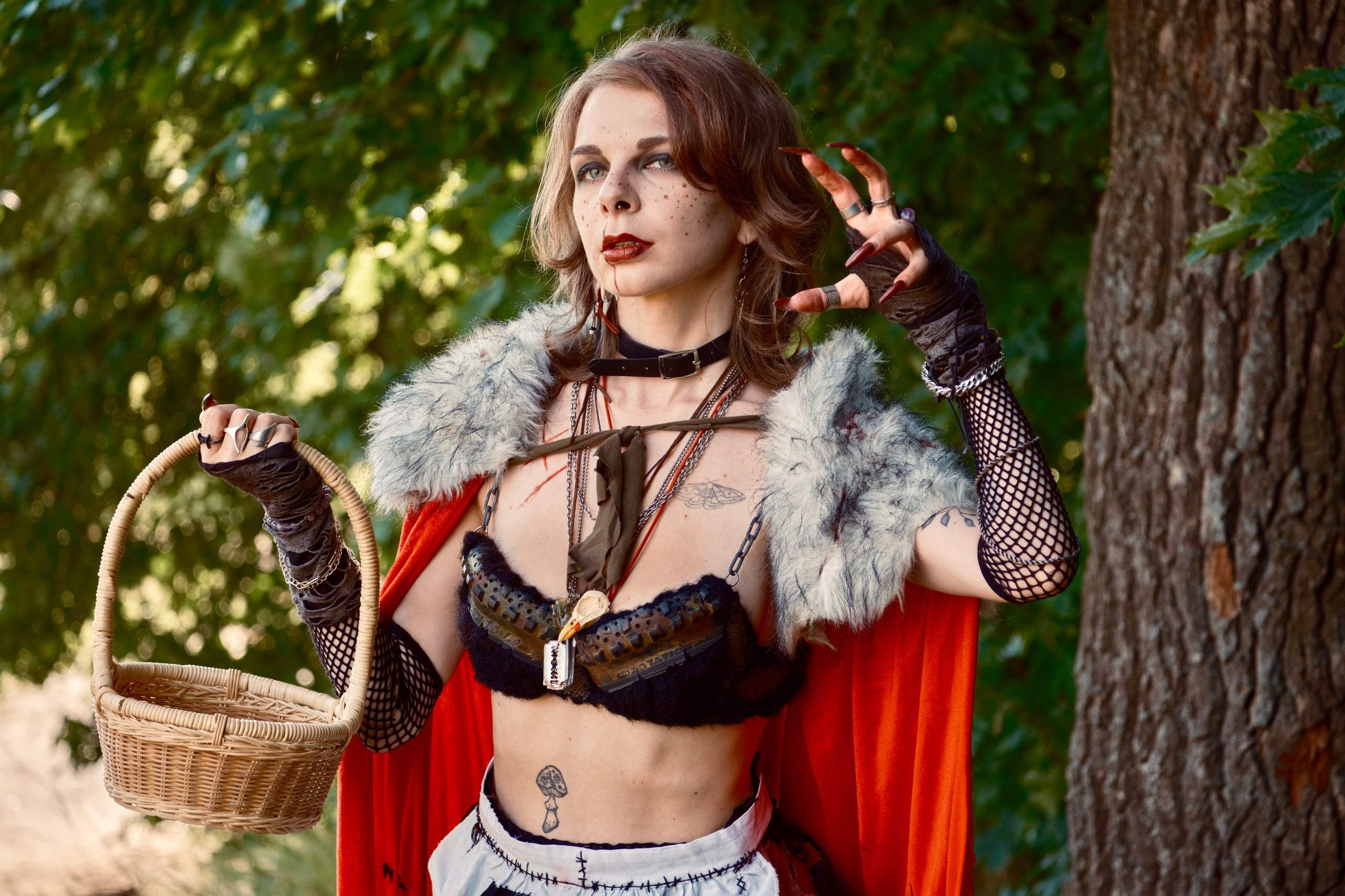 Девушка в красном плаще с корзиночкой гуляет в лесу