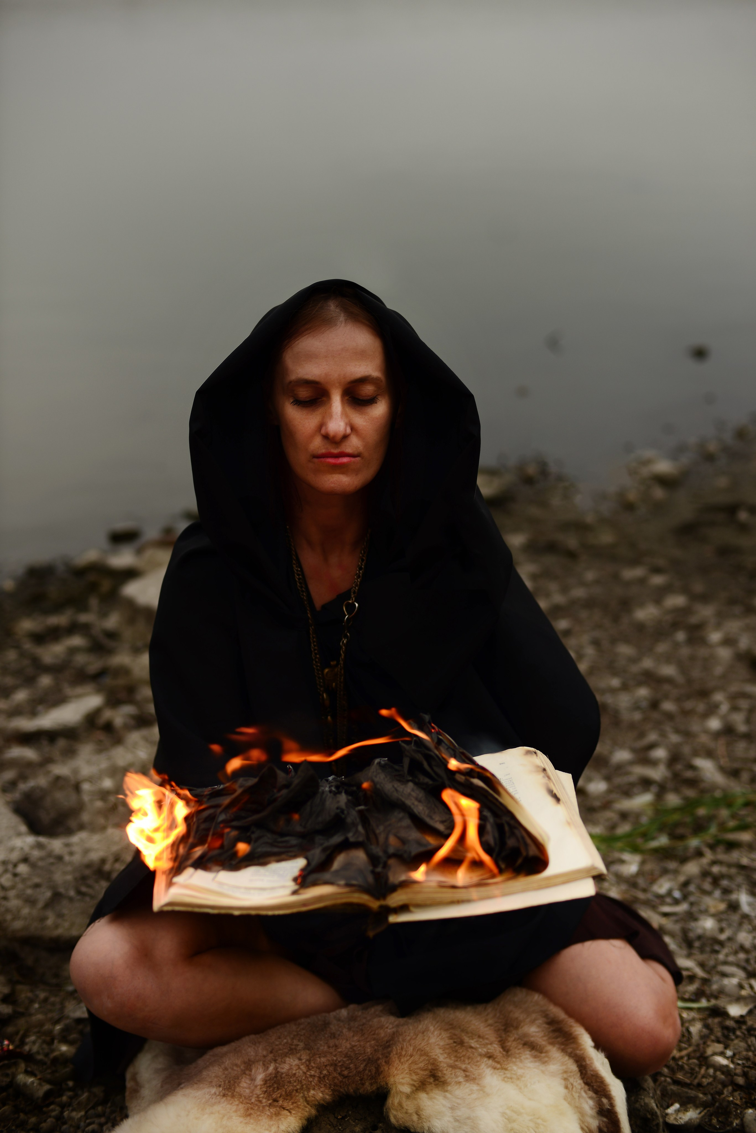 Творческая необычная фотосессия в Луганске. Луганское море. Девушка  в черном длинном ведьма сжигает книгу.