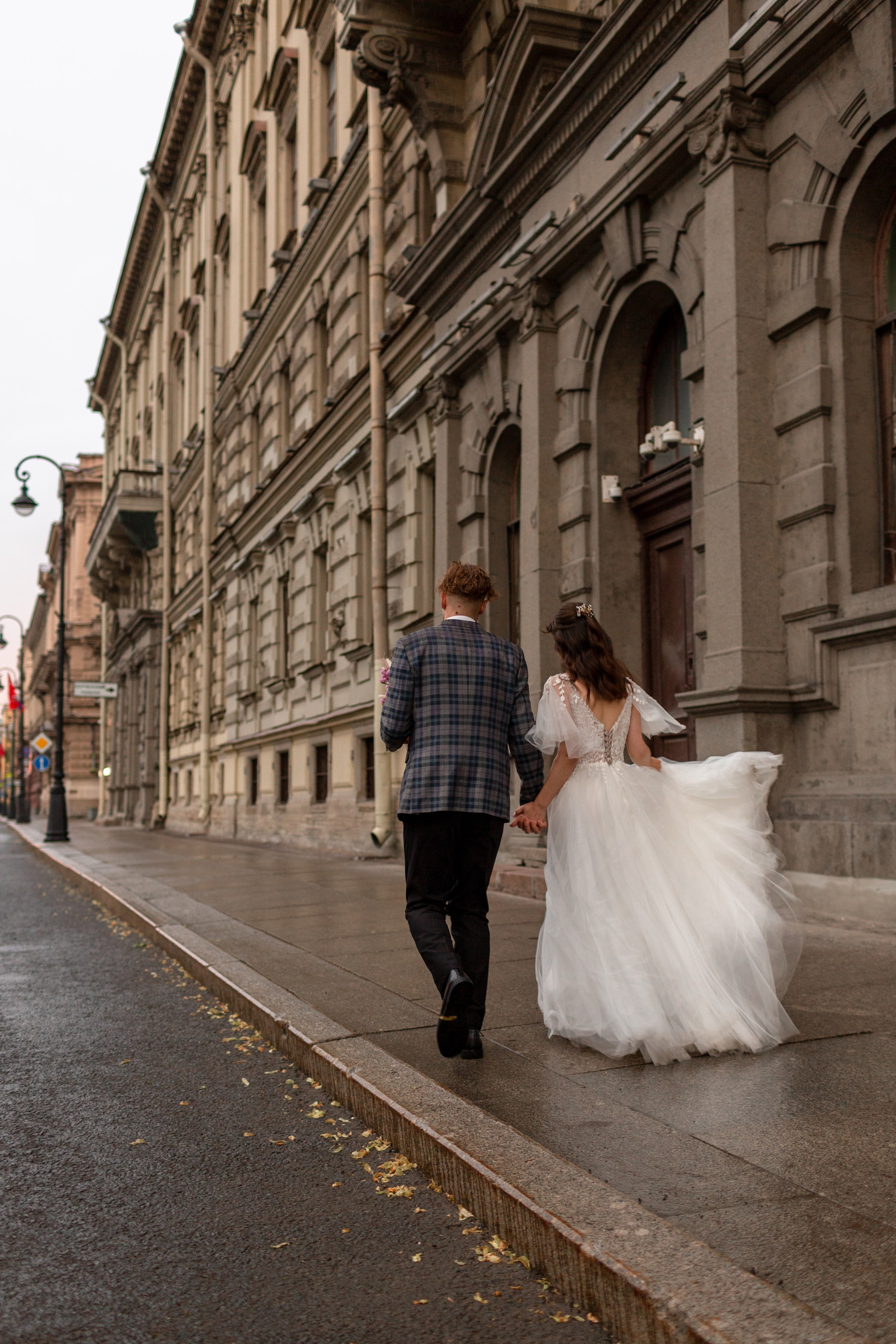 Невеста держит подол платья на ветру