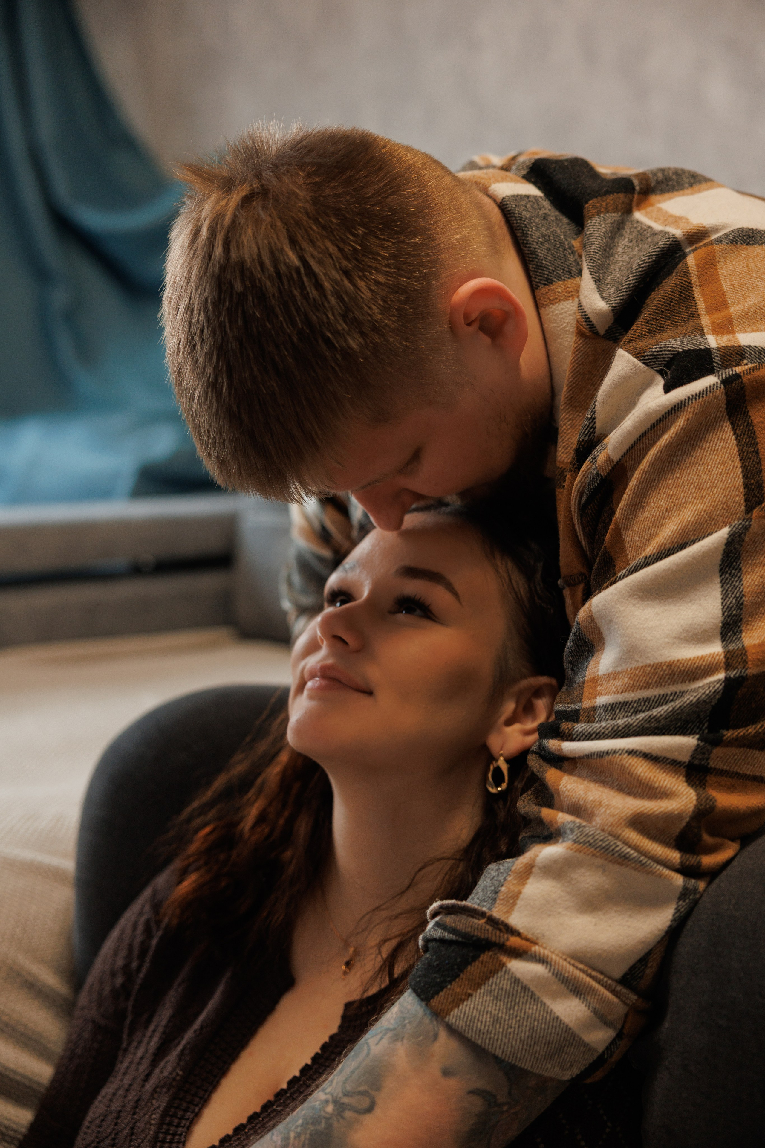 Фотосессия Love Story в Хабаровске: парень нежно целует девушку в лоб. Уютная домашняя или студийная съемка для влюбленных в теплых тонах