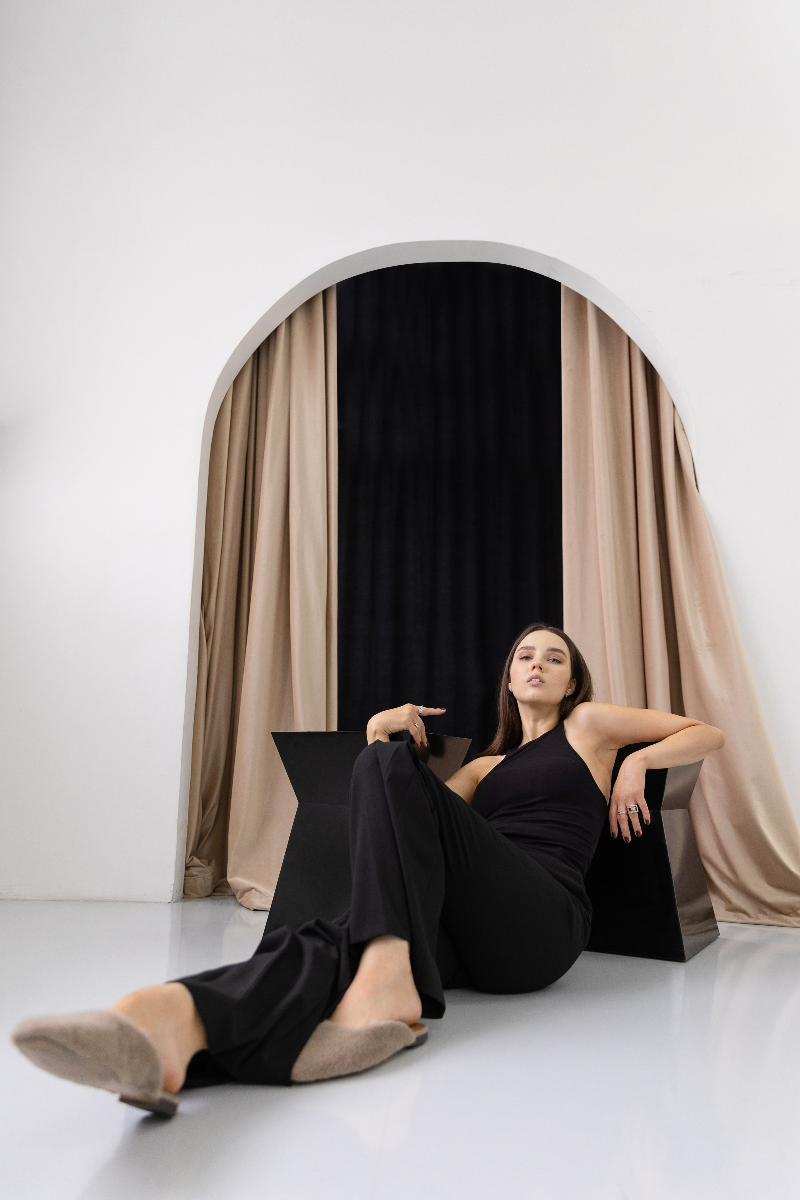 Девушка в чёрной одежде лежит на полу облокотив локти на кубики