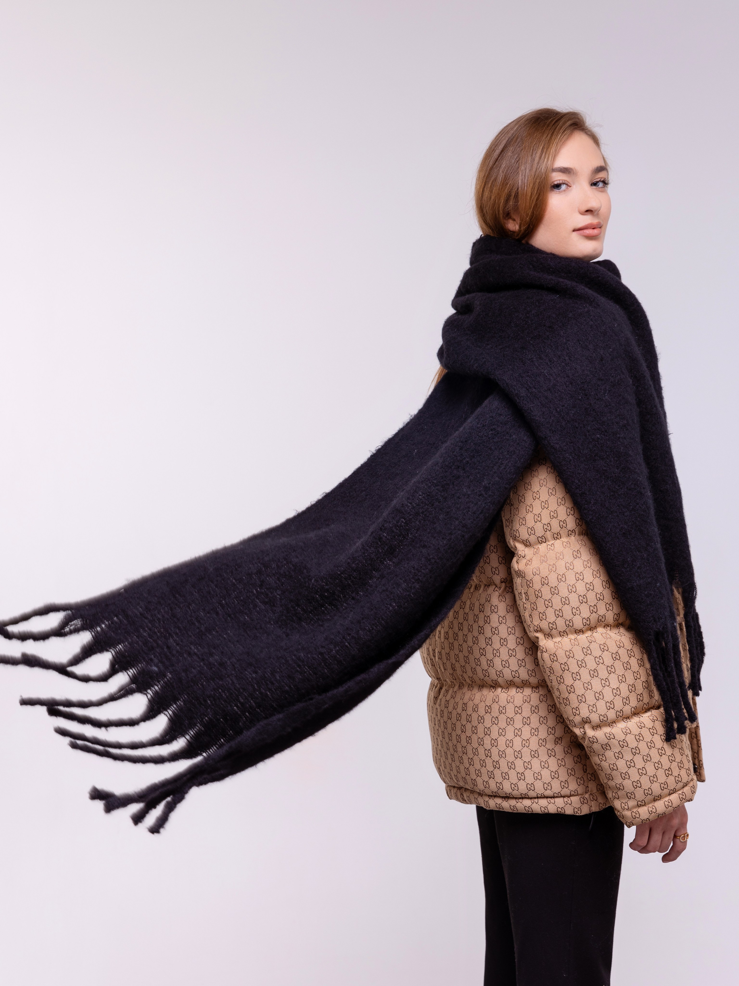 Длинный палантин черного цвета развивается у девушки за спиной.