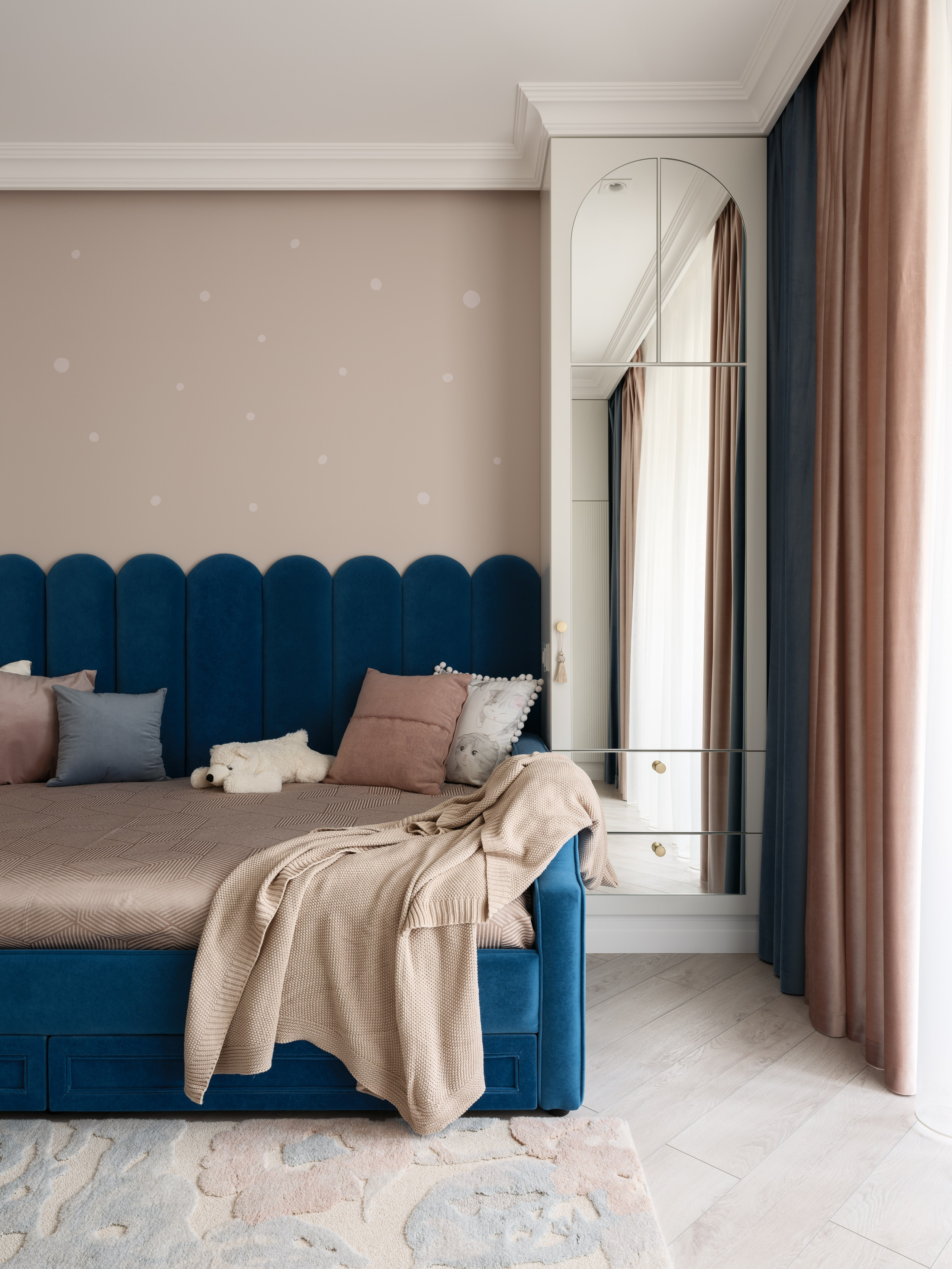 Детская с мягким синим диваном-кроватью, бежевым пледом и акцентными подушками. Рядом шкаф с зеркалом и длинные шторы в пастельных оттенках. Дизайн Евгении Ермошиной, фото Сергея Денисенко.