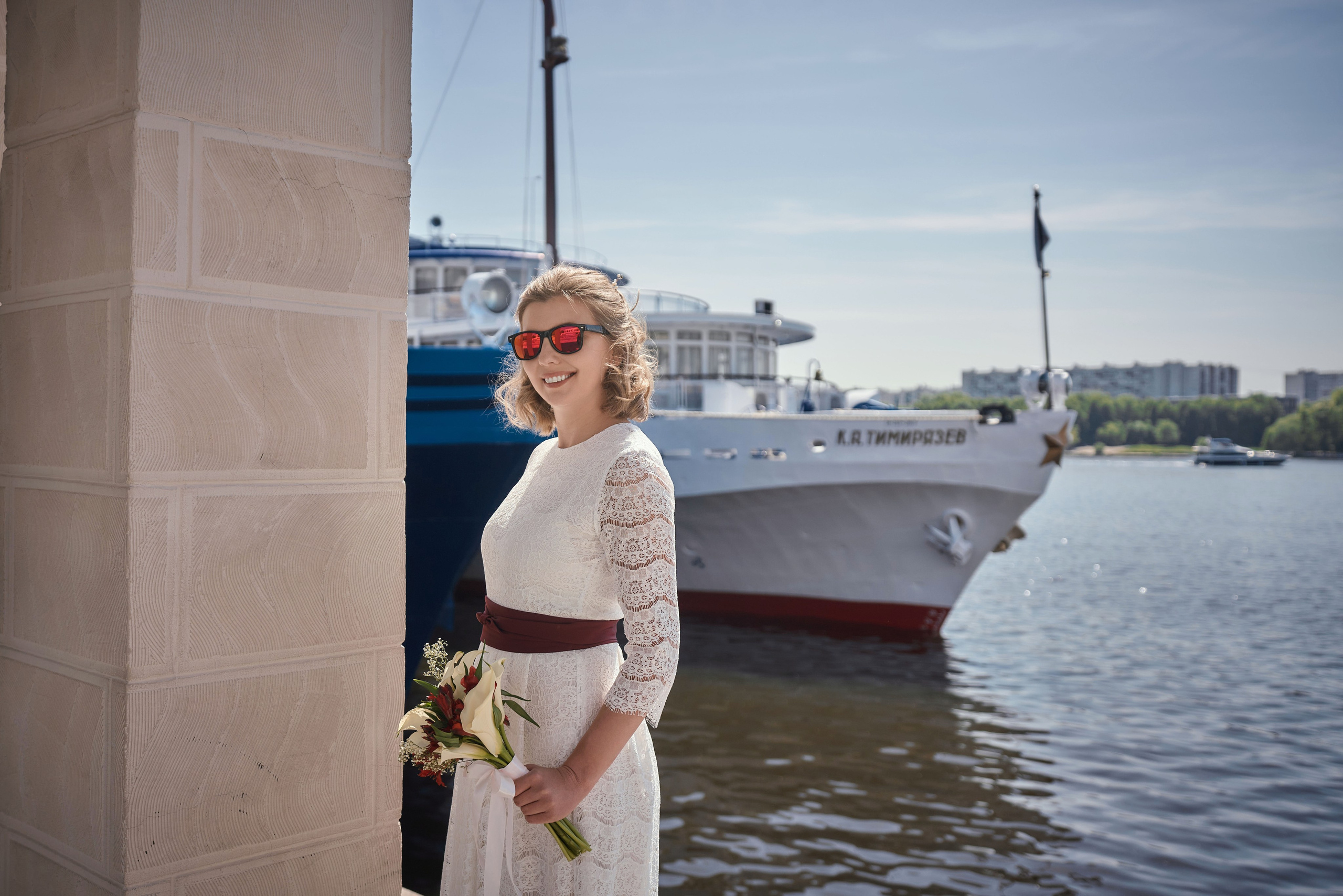 невеста в очках на фоне реки и носа корабля