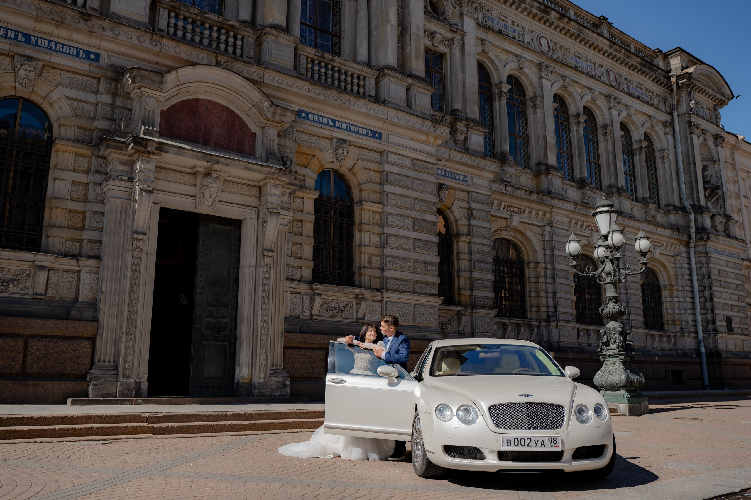 Свадебная фотосессия у Академии Штиглица с автомобилем. Жених красиво обнимает невесту у свадебного автомобиля