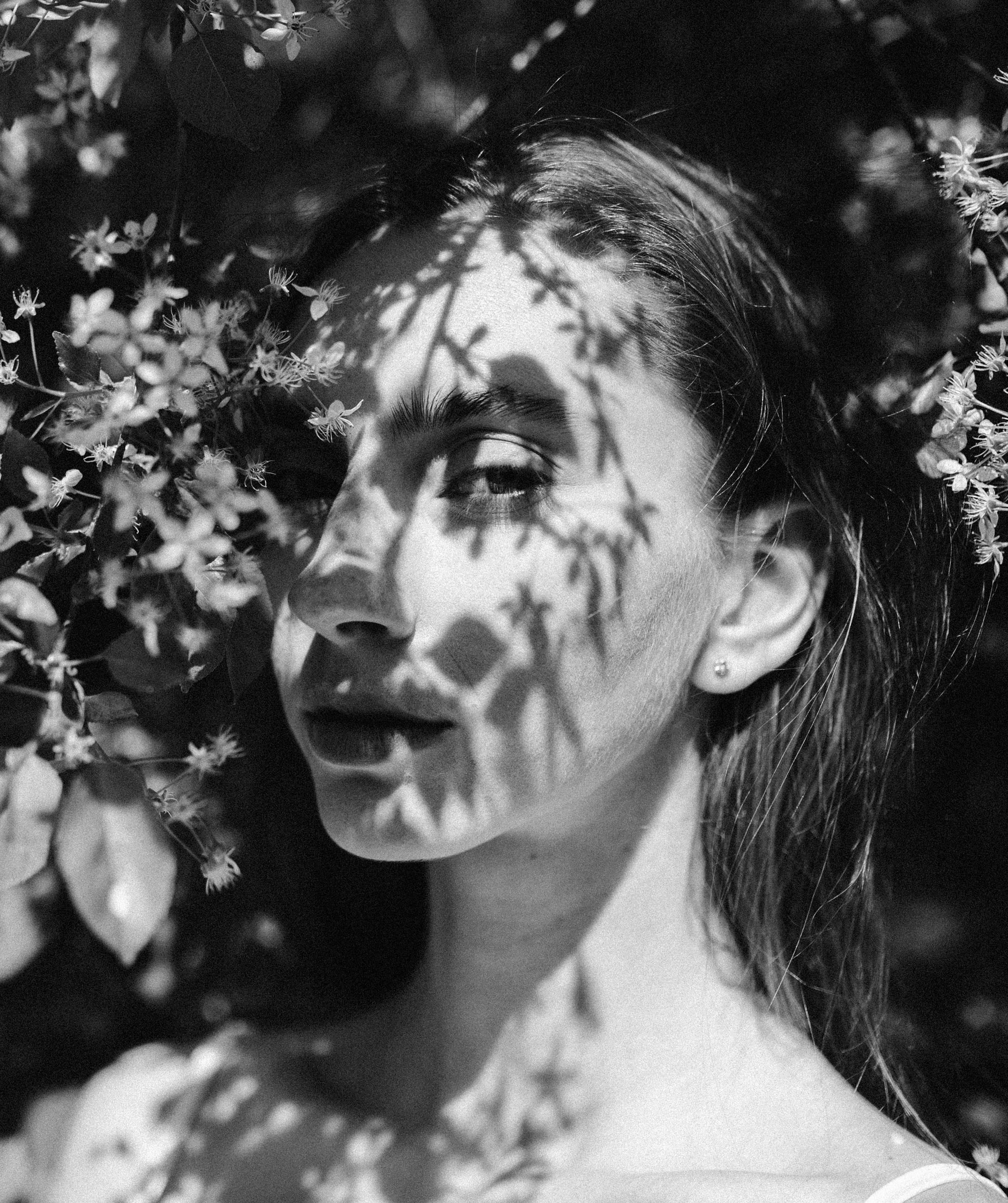 Тени от цветущего дерева на лице девушки крупным планом