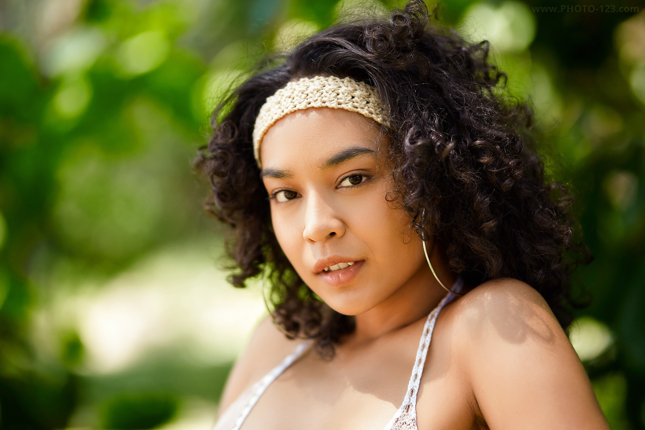 Natural light beauty portrait of a woman with curly hair photographed outdoors, surrounded by greenery during a fashion and lifestyle photoshoot in Phu Quoc, Vietnam