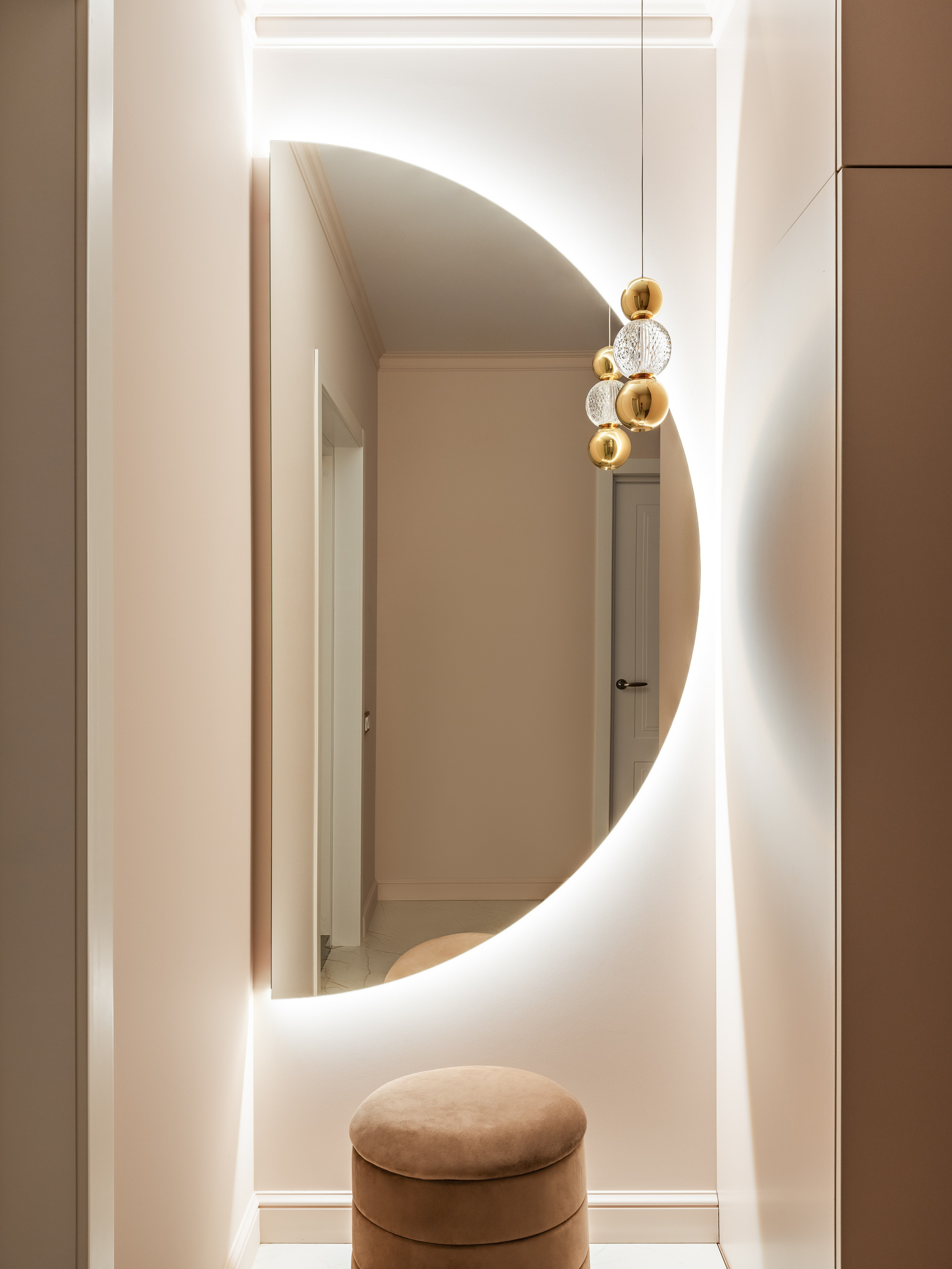 Элегантный подвесной светильник с золотыми элементами и хрустальной сферой отражается в зеркале, создавая акцент в современном интерьере прихожей. Дизайн Наталья Бунеева, стилист Наталья Якушева, фотограф Сергей Денисенко.