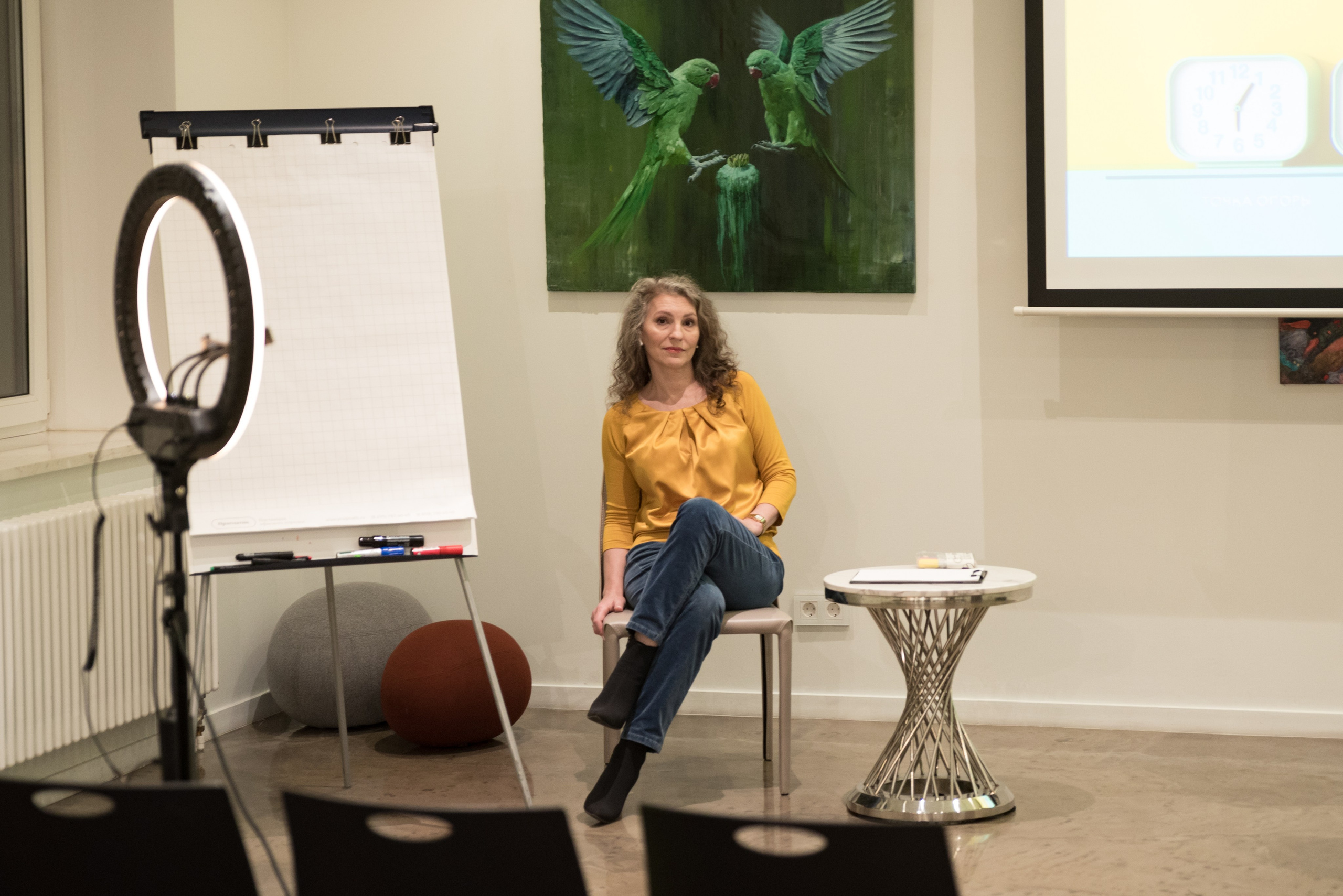 Женщина сидит в лекционном зале около доски.