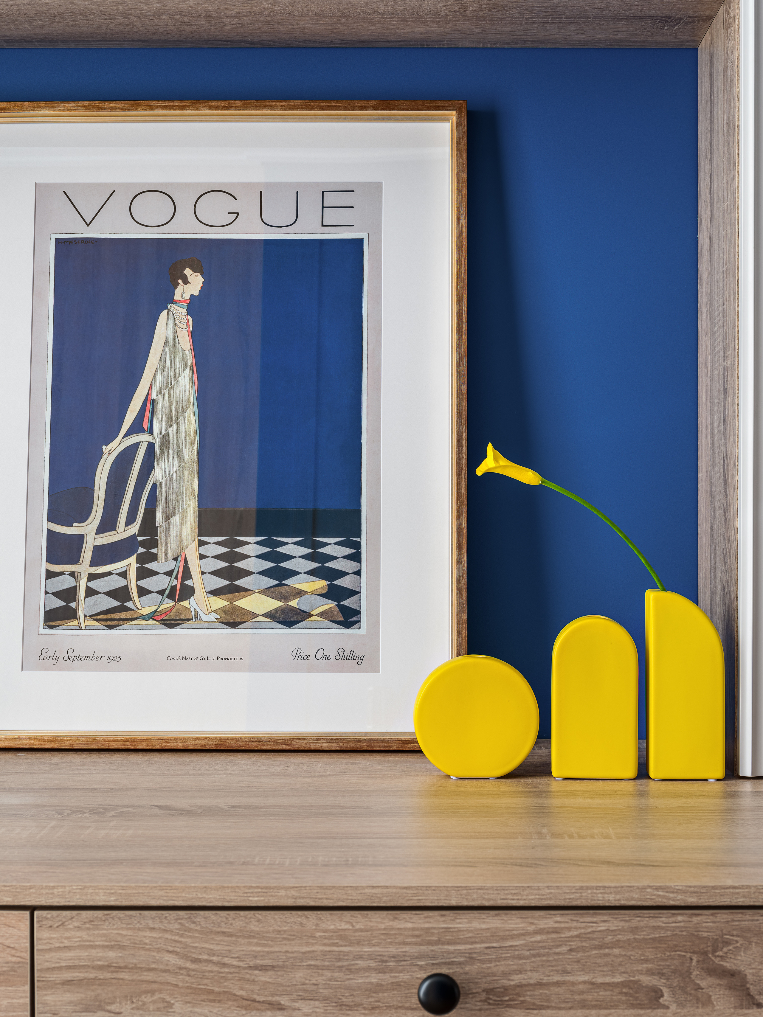 Деталь интерьера спальни: постер Vogue в деревянной раме на фоне синей стены и стильный желтый декор. Работа дизайнера Оксаны Магомедовой, стилиста Натальи Якушевой, фотография Сергея Денисенко.