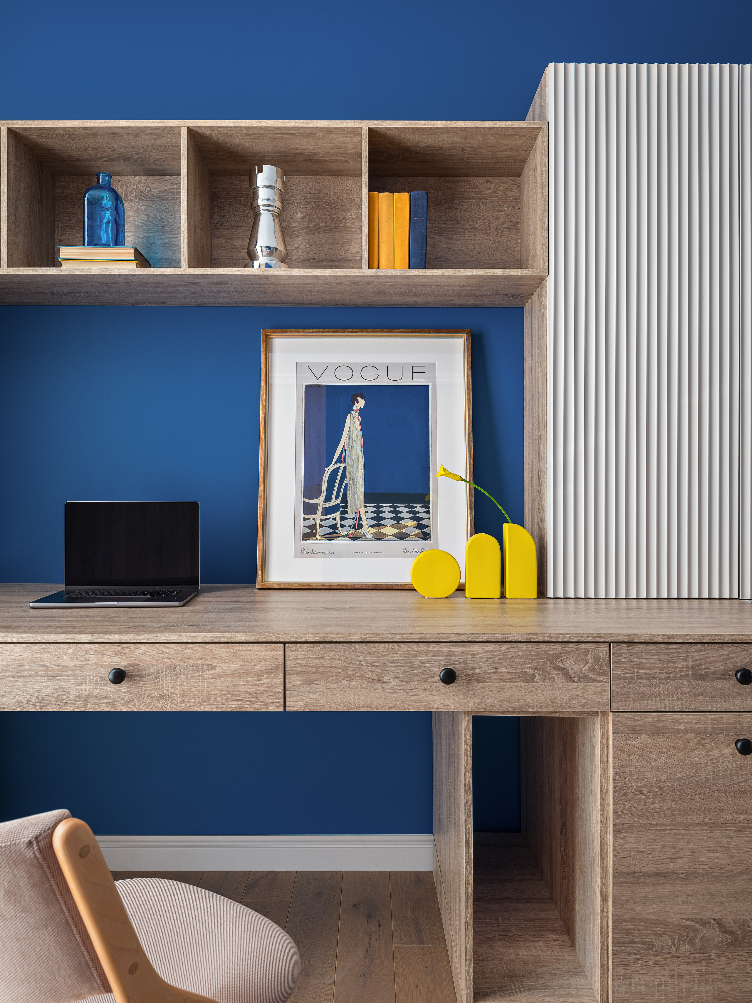 Рабочая зона в спальне: деревянный стол с ящиками, синий фон стены, декор с постером Vogue и яркими желтыми акцентами. Интерьер создан дизайнером Оксаной Магомедовой, стилист Наталья Якушева, фото Сергей Денисенко.