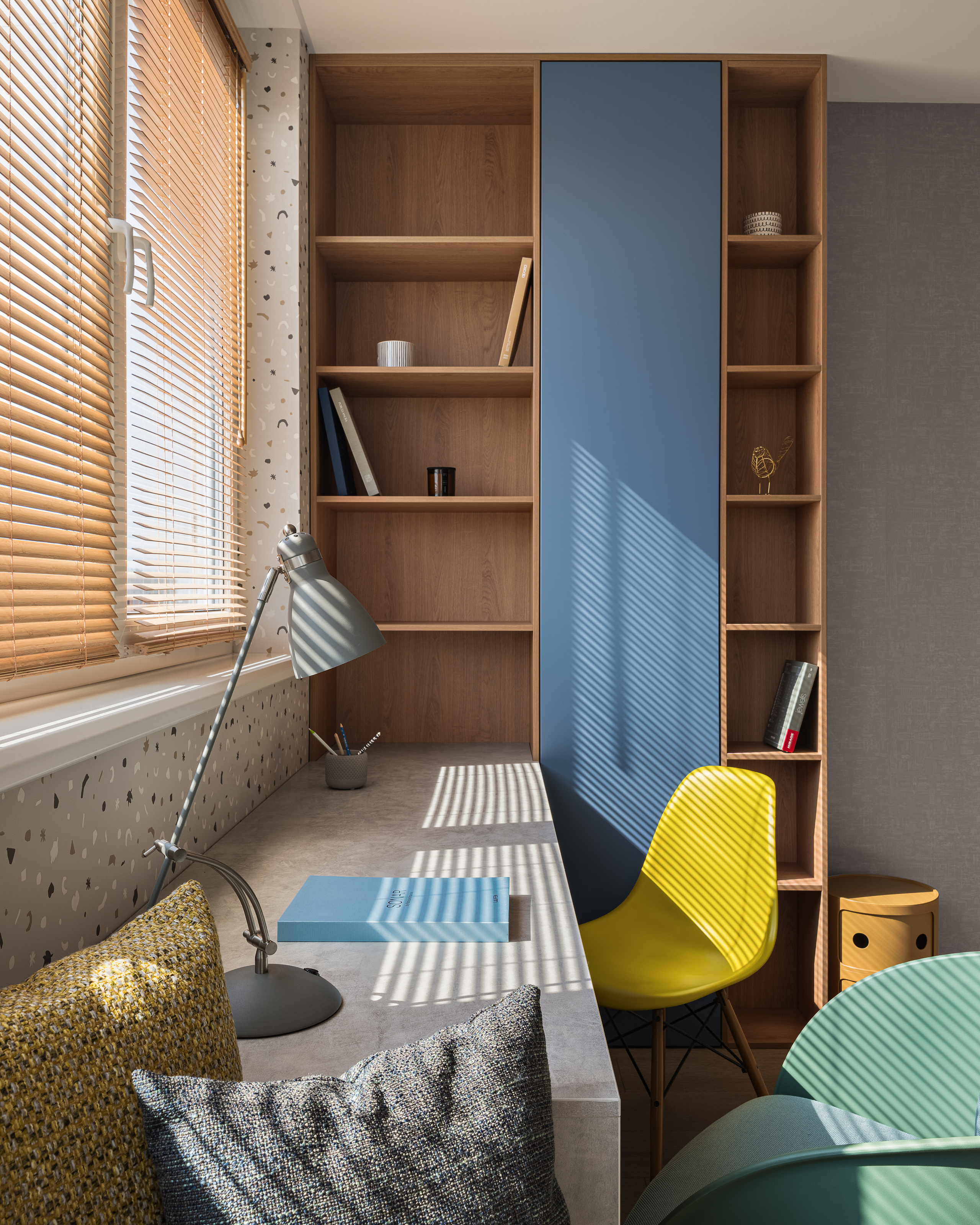 Функциональное рабочее место с длинным столом у окна, настольной лампой, жёлтым дизайнерским стулом и шкафом с открытыми полками. Дизайн разработан Алёной Сверловой, съёмка интерьера – Сергей Денисенко.