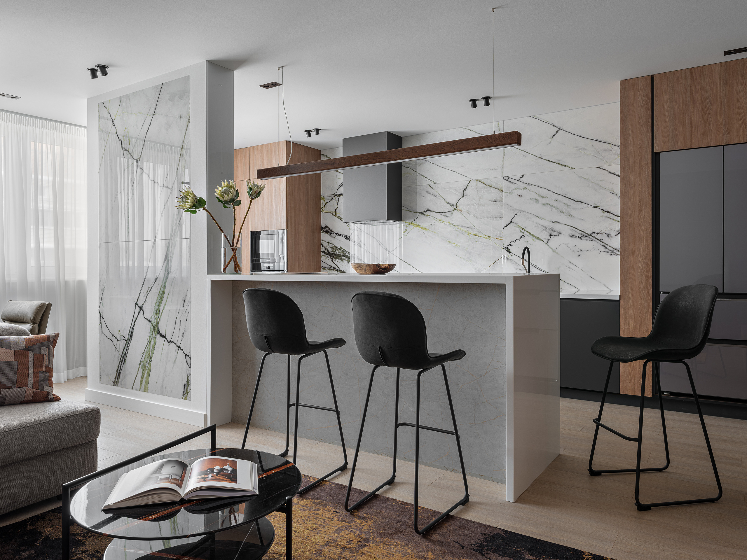 Общий вид кухни-гостиной: барная стойка с высокими стульями, мраморные панели с зелеными прожилками, встроенные шкафы и уютная зона отдыха с диваном. Автор интерьера дизайнер Алёна Сверлова, фото Сергей Денисенко.