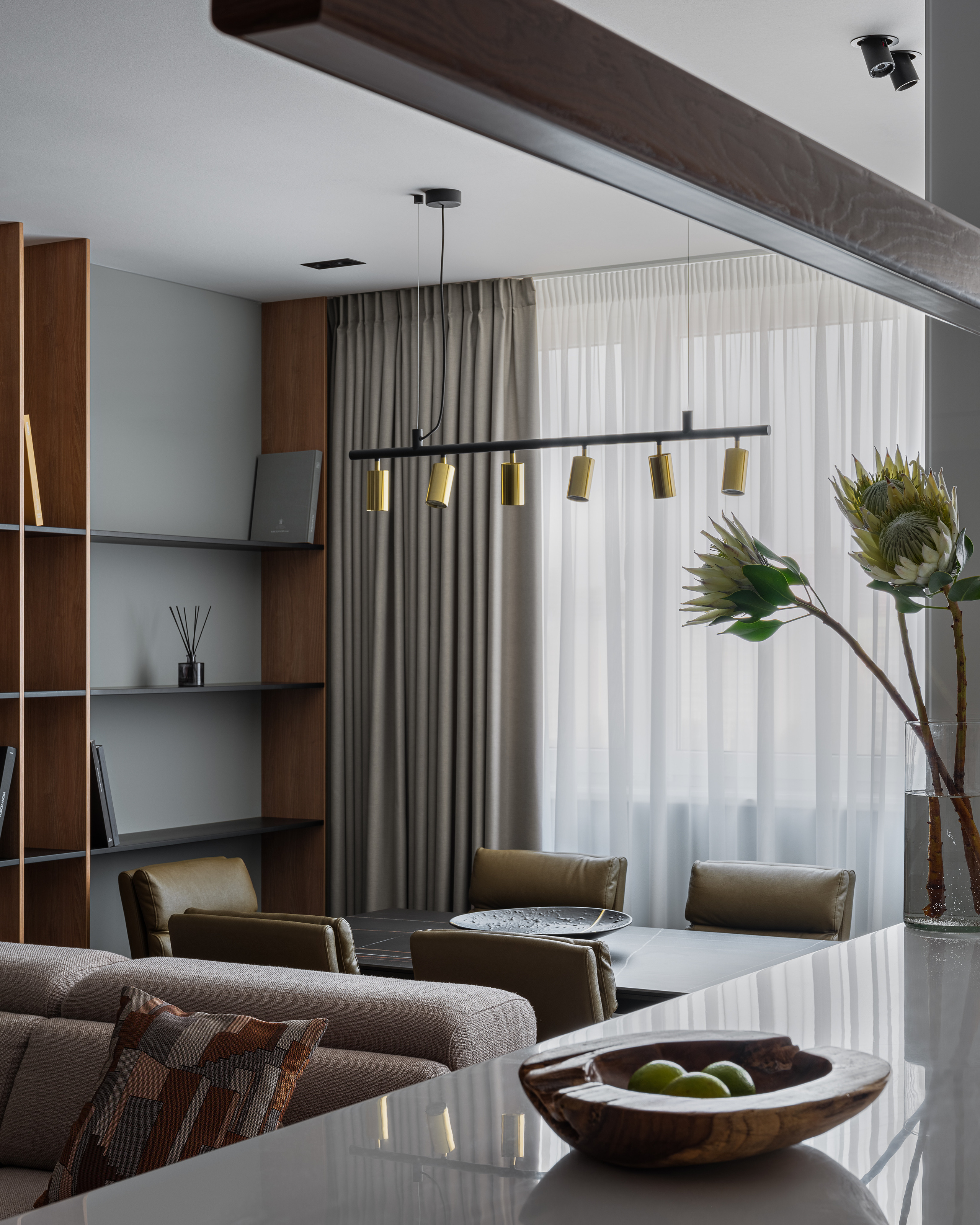 Элегантный интерьер кухни-гостиной: вид на обеденный стол с кожаными стульями, барную стойку из камня и декоративные аксессуары в вазе. Светлый современный проект дизайнера Алёны Сверловой, фото Сергей Денисенко.