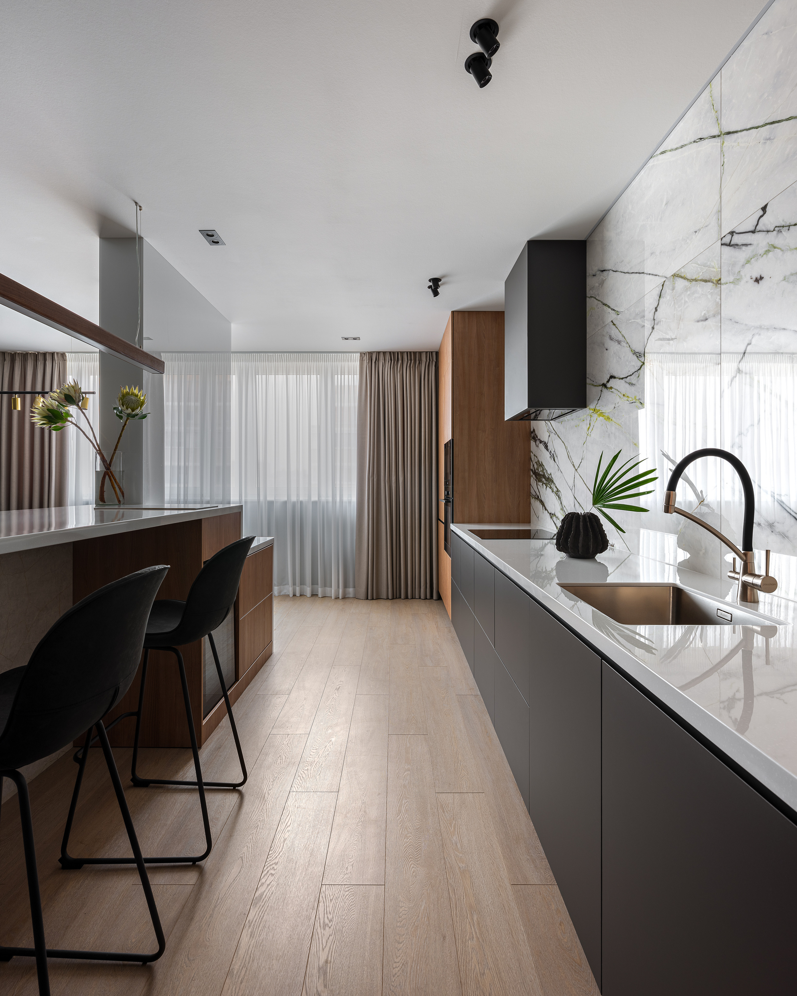 Современная кухня с длинной столешницей, встроенной мойкой, фасадами в матовом графитовом цвете и барной стойкой с высокими стульями. Акцент — мраморная стена с зелёными прожилками. Интерьер Алёны Сверловой, фото Сергей Денисенко.