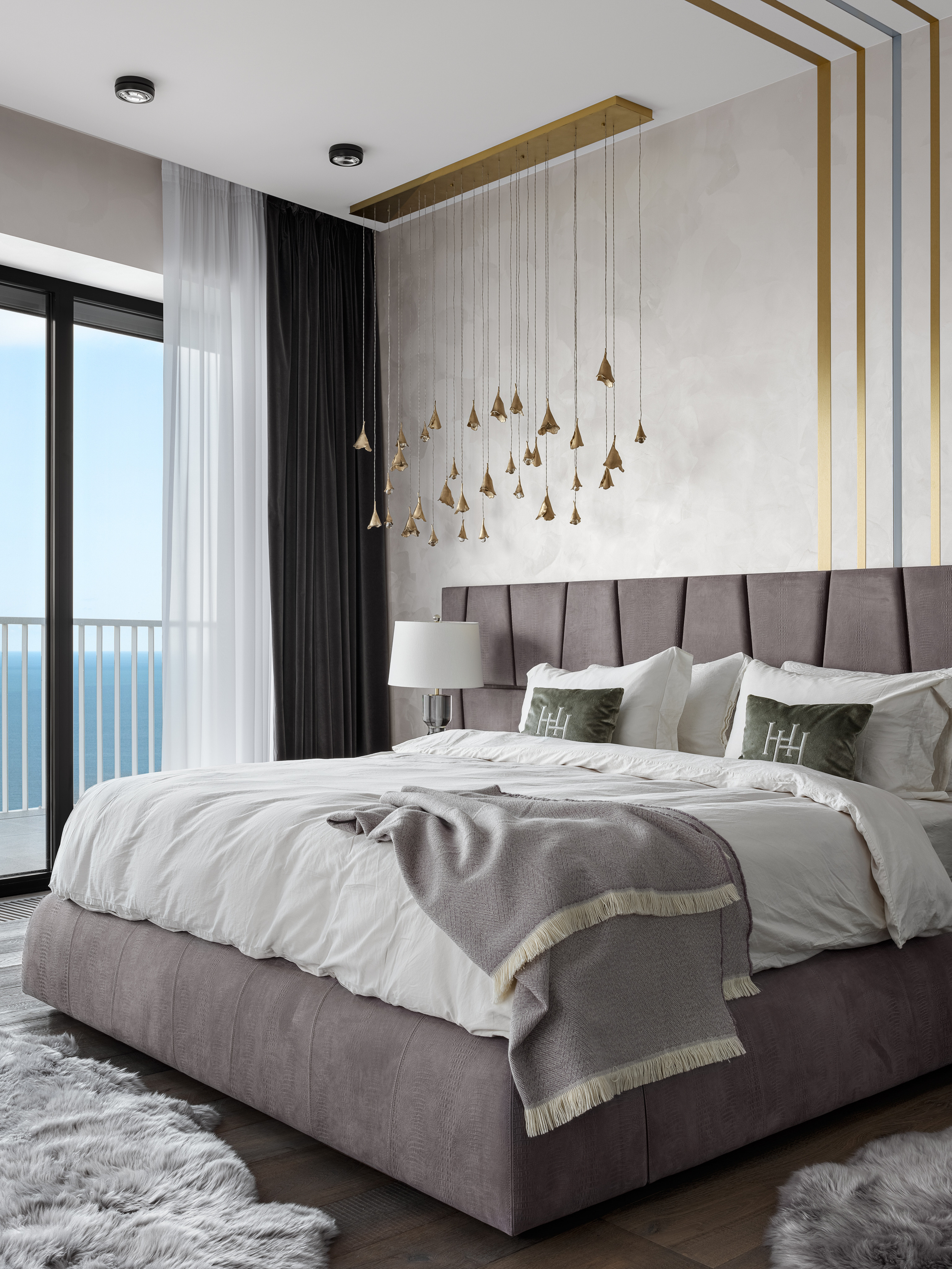 Современная спальня с панорамным видом на море, большим мягким изголовьем, подвесными золотыми светильниками и уютным текстилем в серо-фиолетовых оттенках. Стилист Екатерина Ракитина, фотограф Сергей Денисенко.