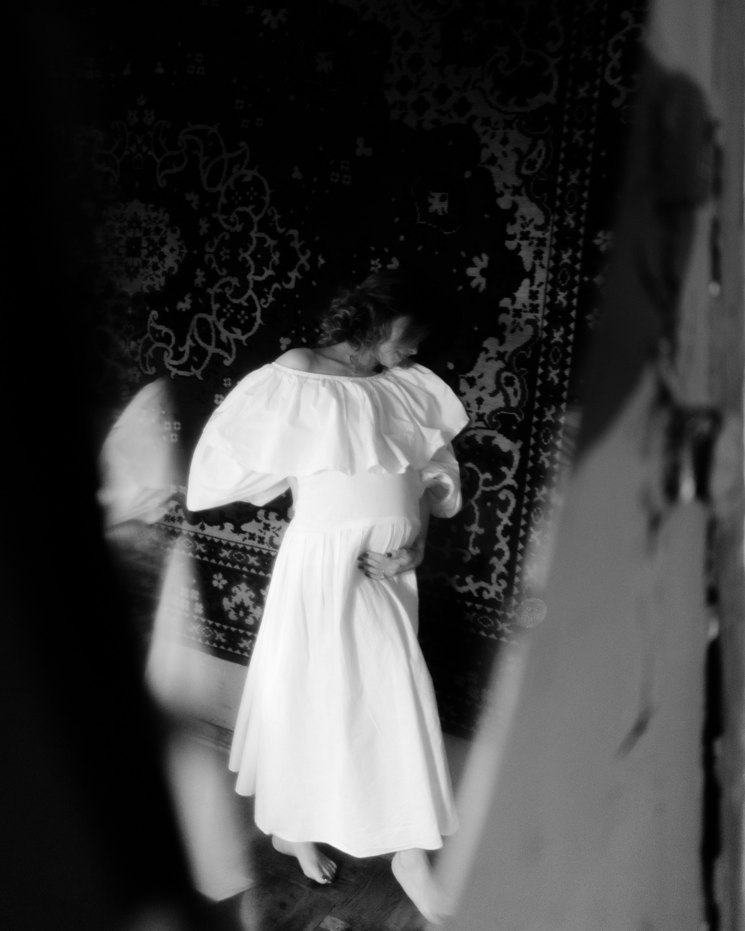 Художественная ч/б фотосъемка беременности: беременная в винтажном белом платье, размытие и движение, атмосферный ретро-портрет в фотостудии СПб.
