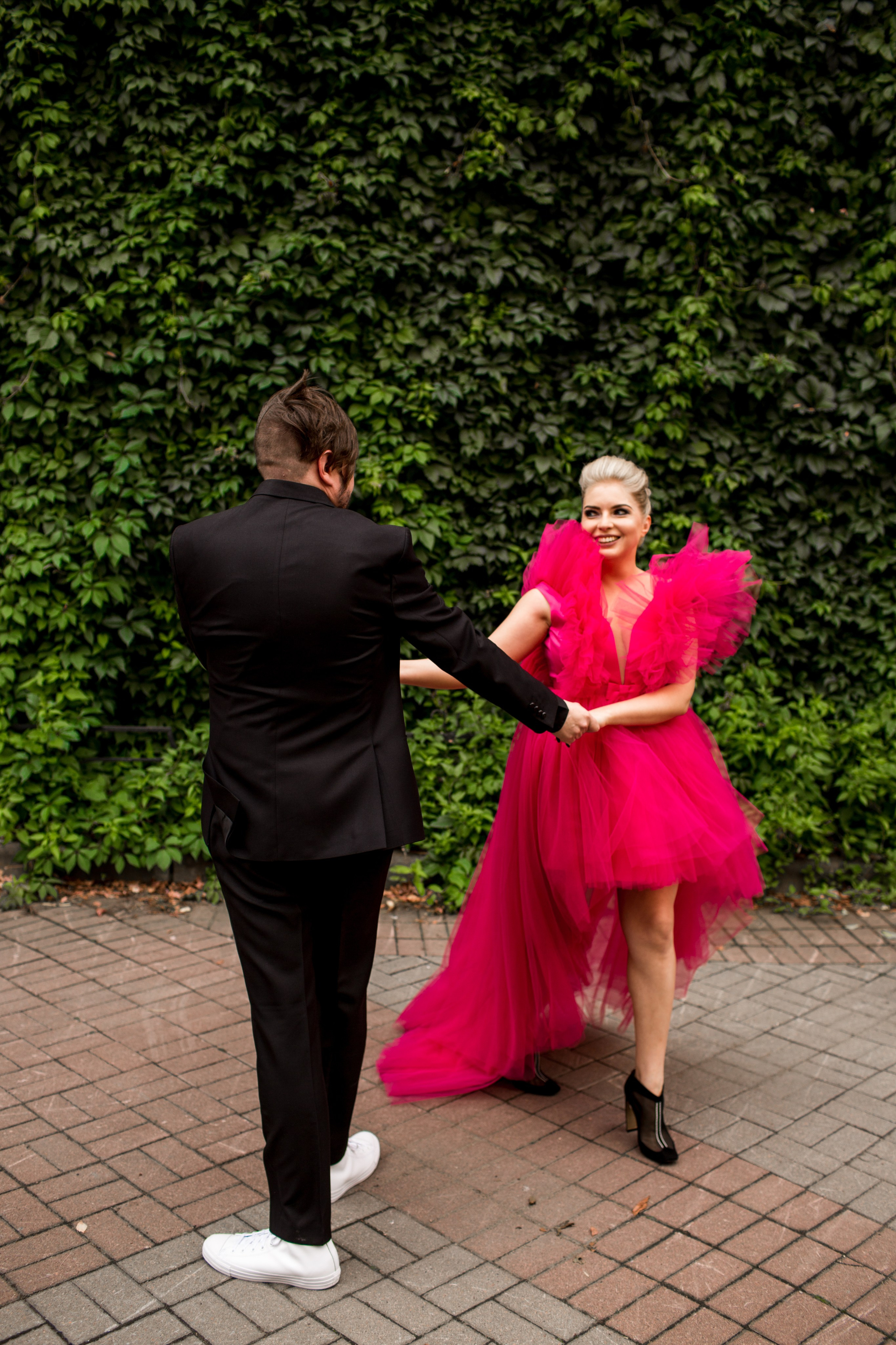 Свадебная пара на фоне фасада, невеста в алом платье и поцелуй