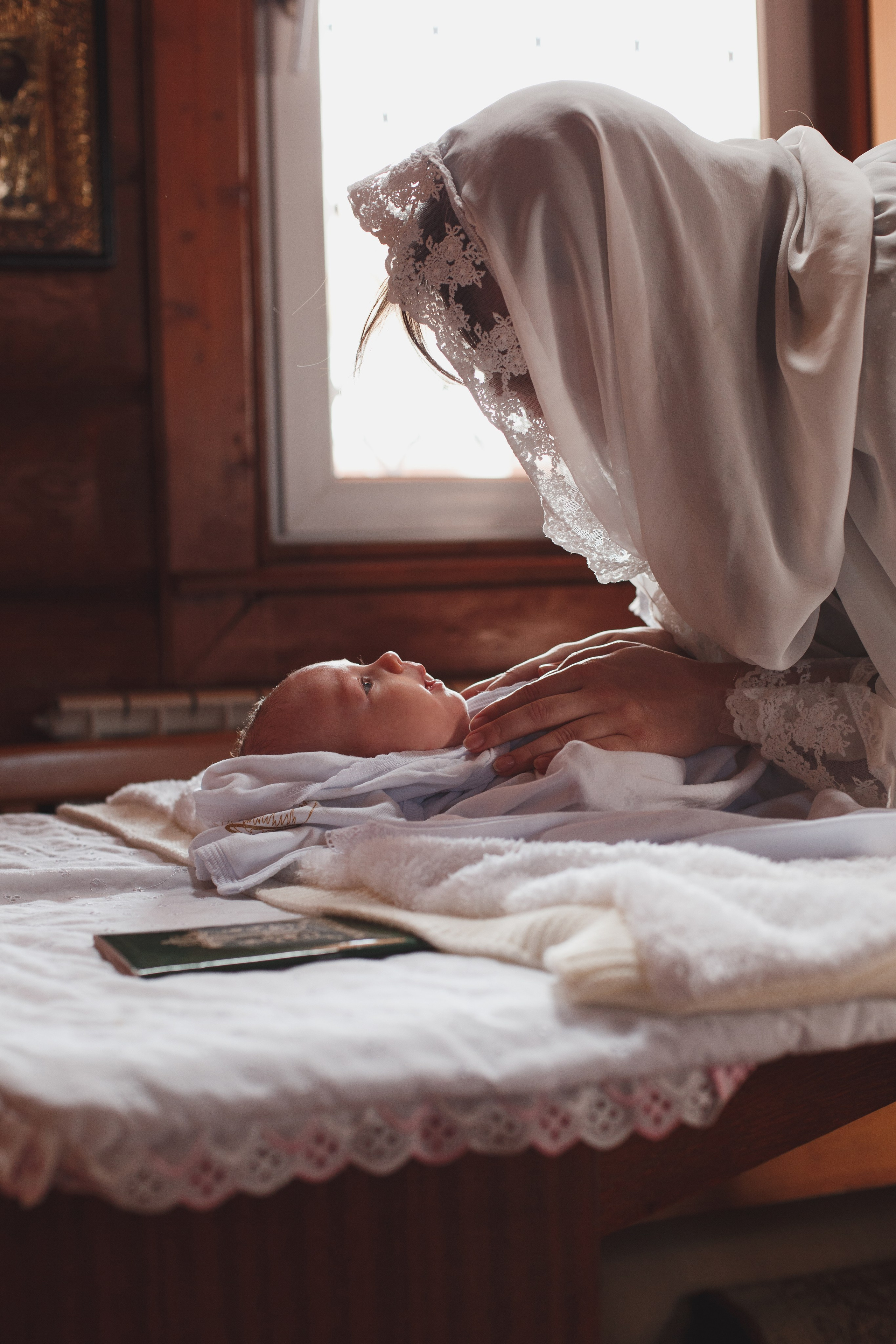 Мама раздевает ребёнка для крещения 