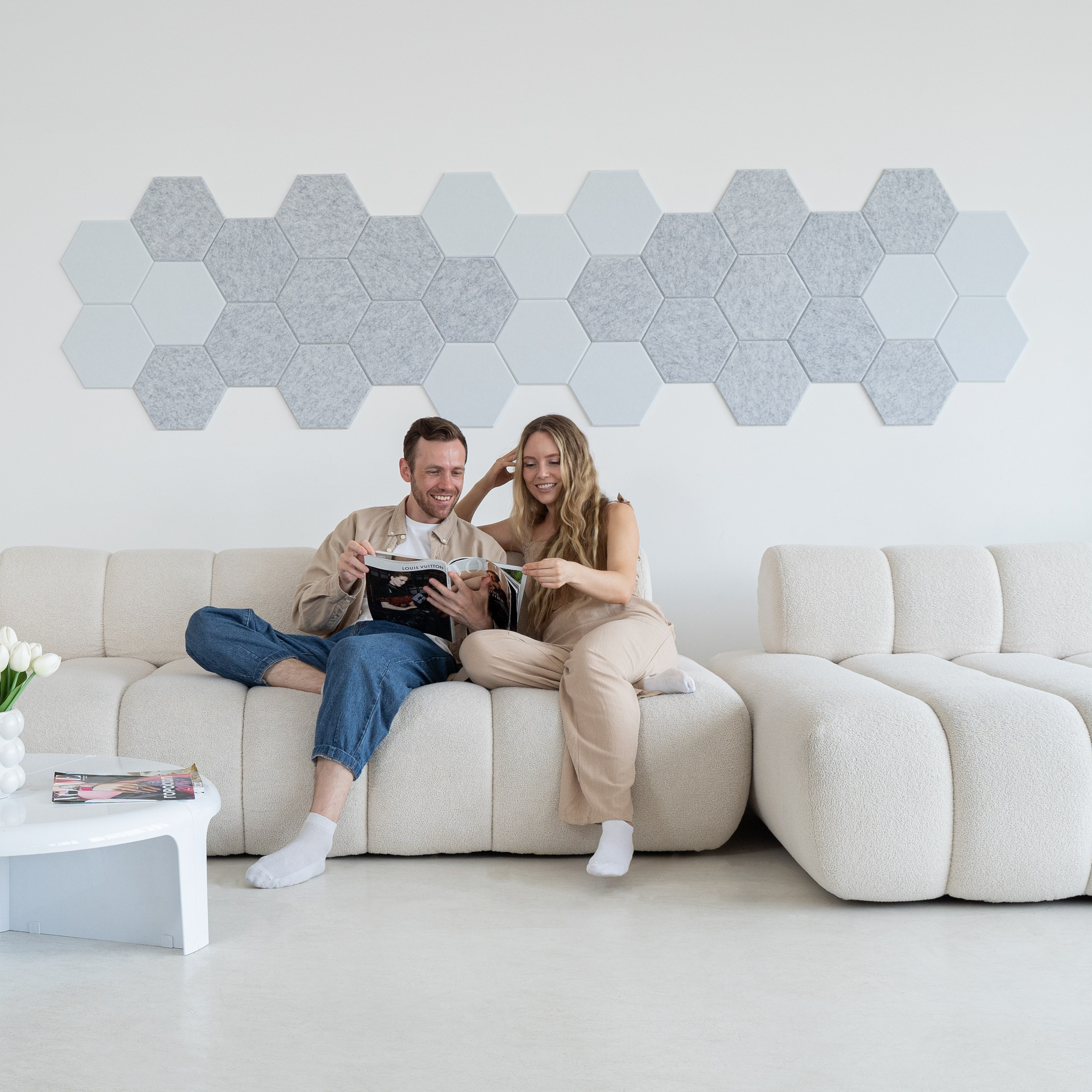 Парень и девушка сидят на бежевом диване и смотрят журнал