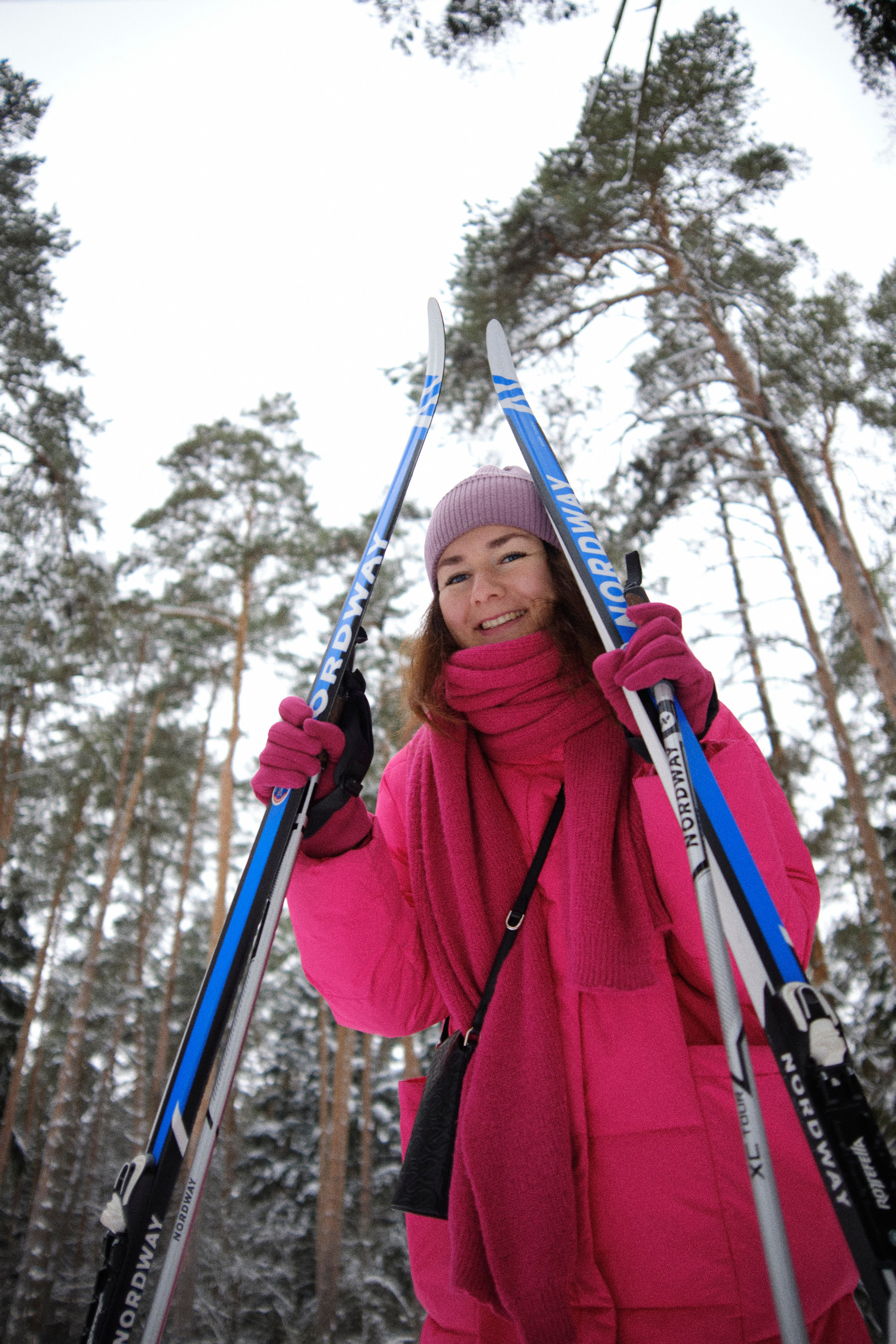 Девушка в яркой одежде в зимнем лесу с лыжами