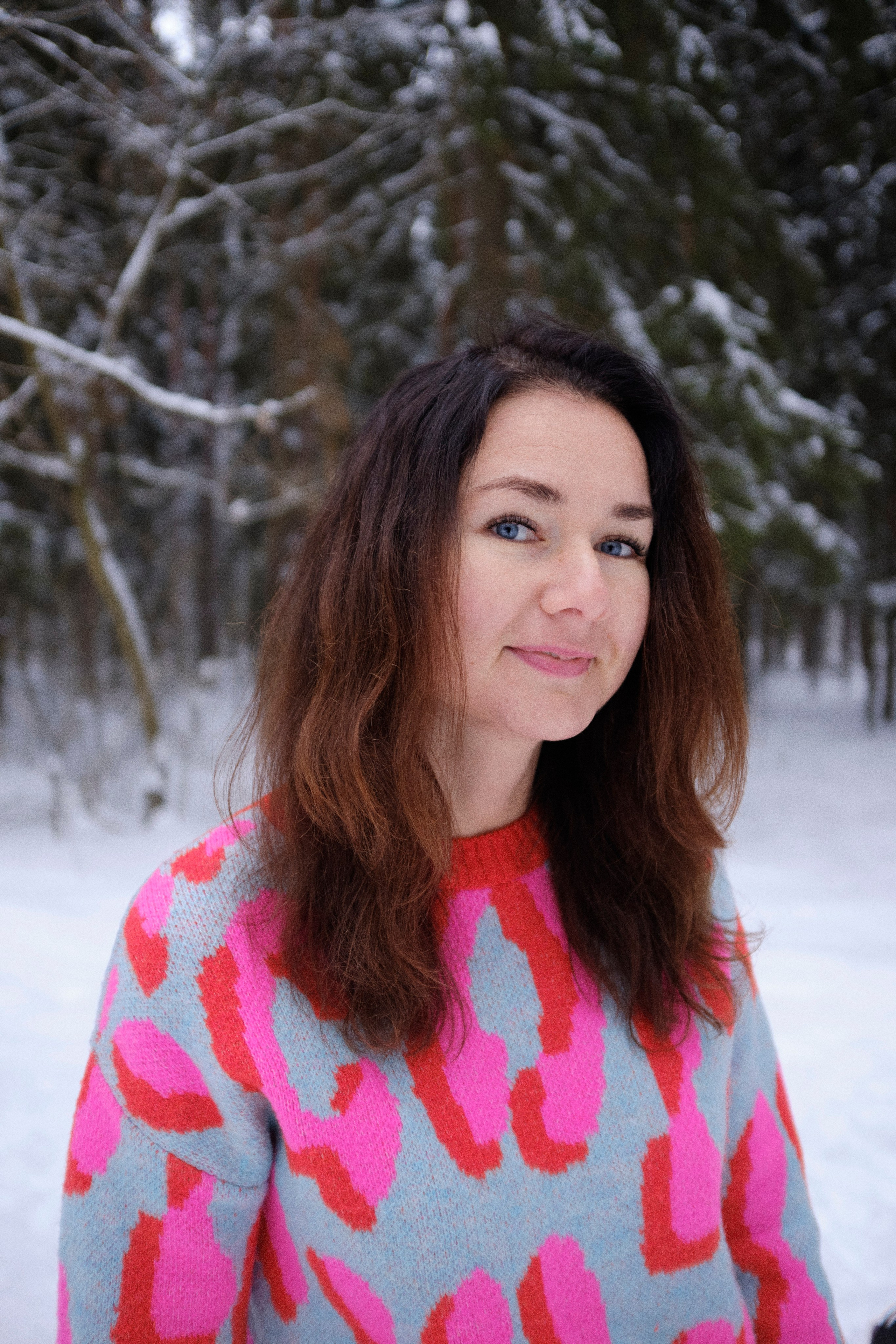 Женщина в ярком свитере на фоне зимнего леса