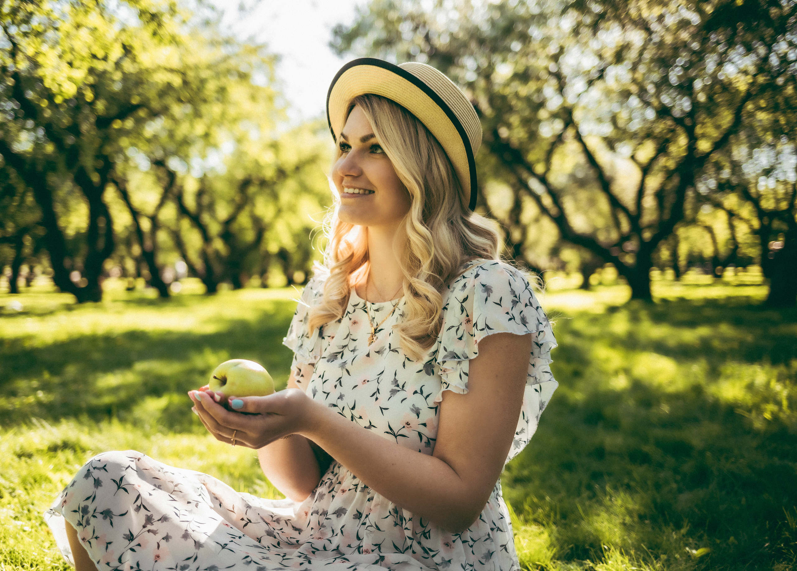 Девушка летняя красивая в яблоневом саду в Коломенском в шляпе и с яблоком