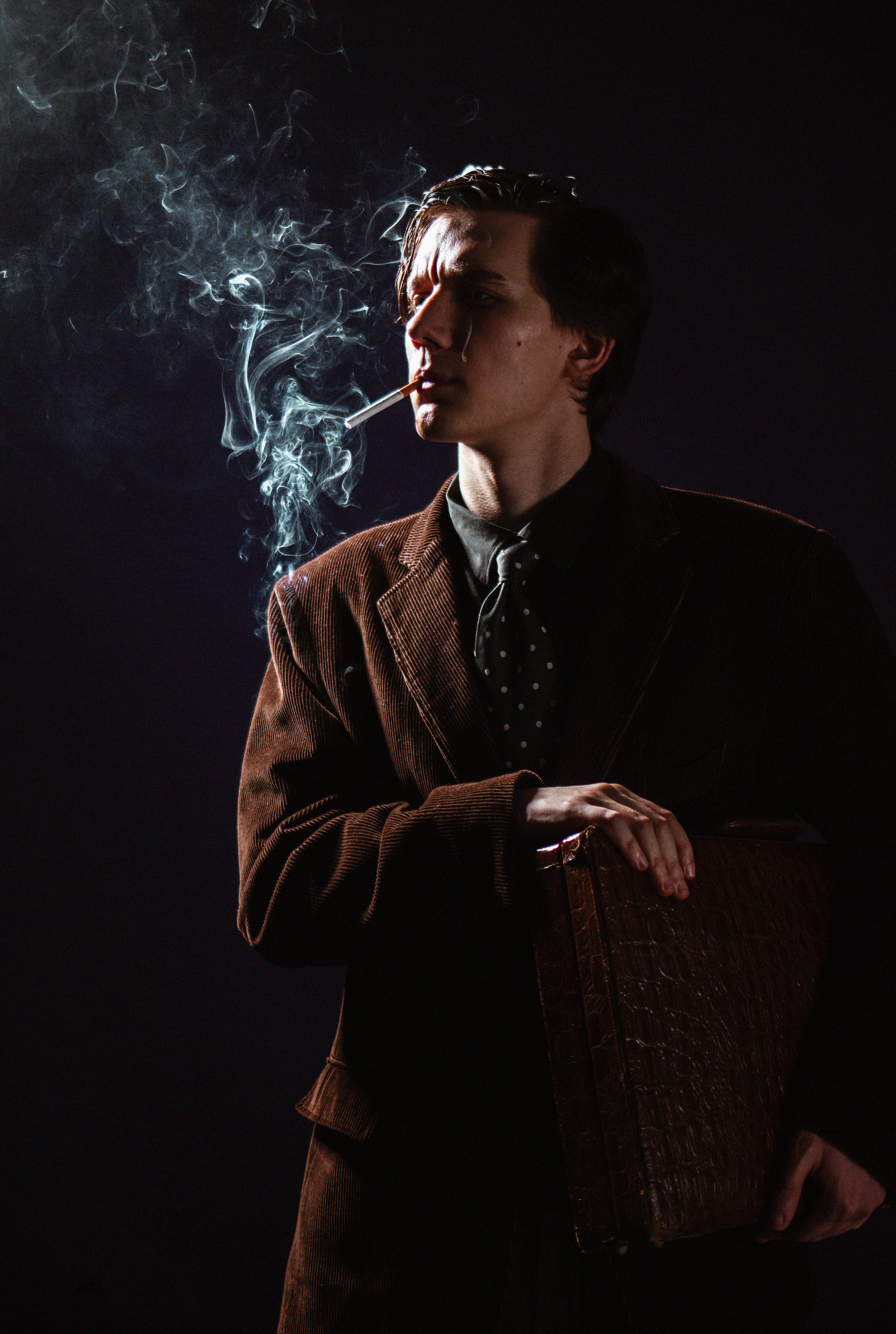 Мужчина курит сигарету в студии фотосессия мужского портрета