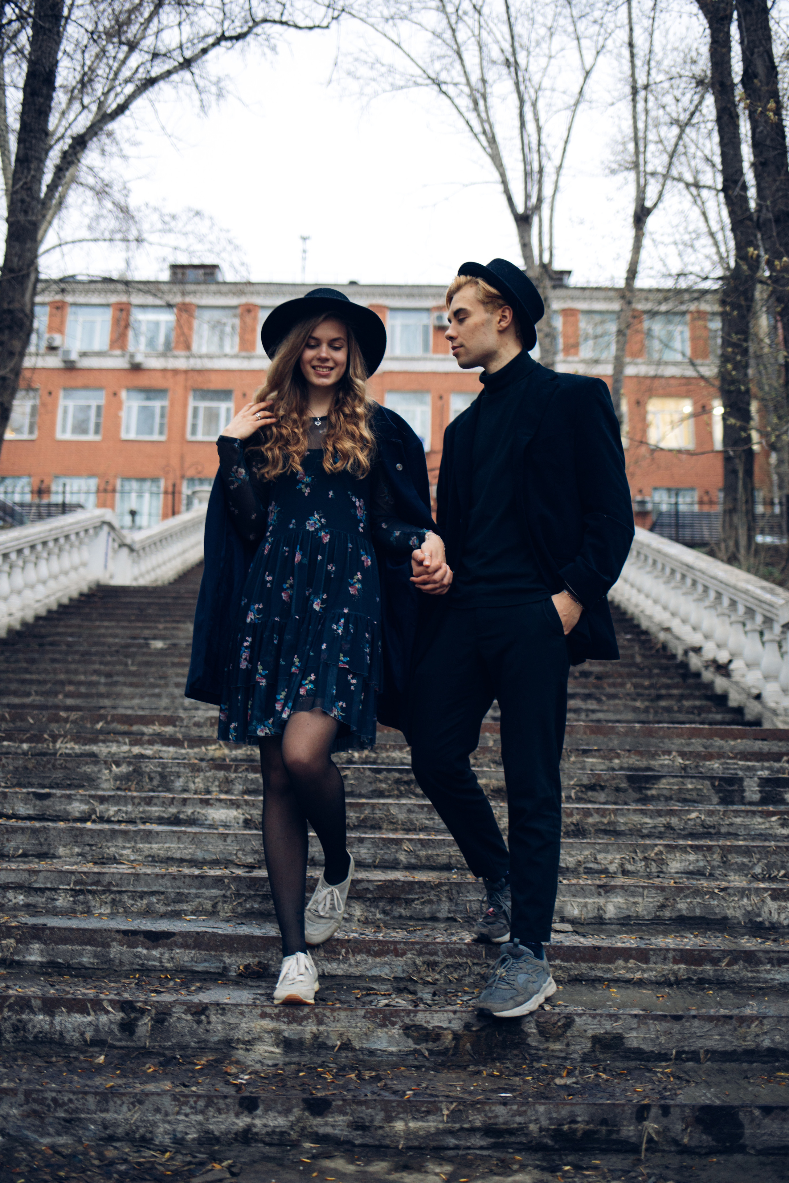 Влюбленная пара спускается со ступенек в облачную погоду 