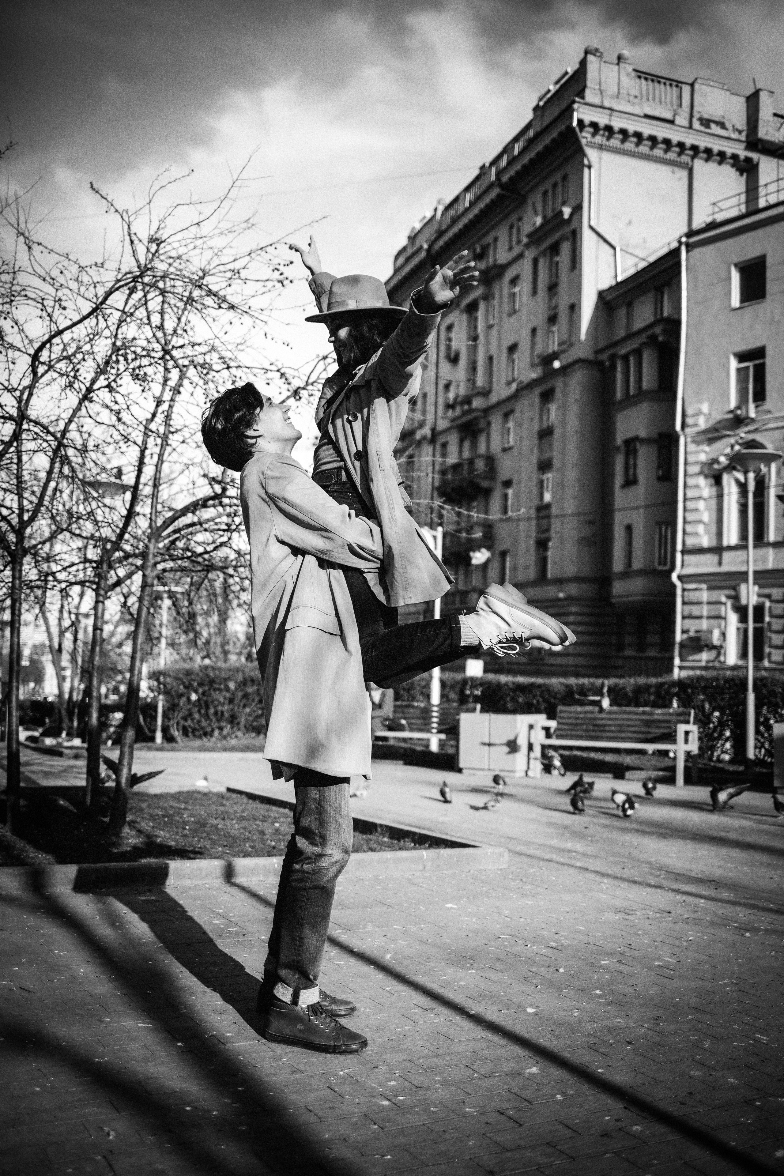 Парень схватил девушку и поднял вверх и спугнул голубей