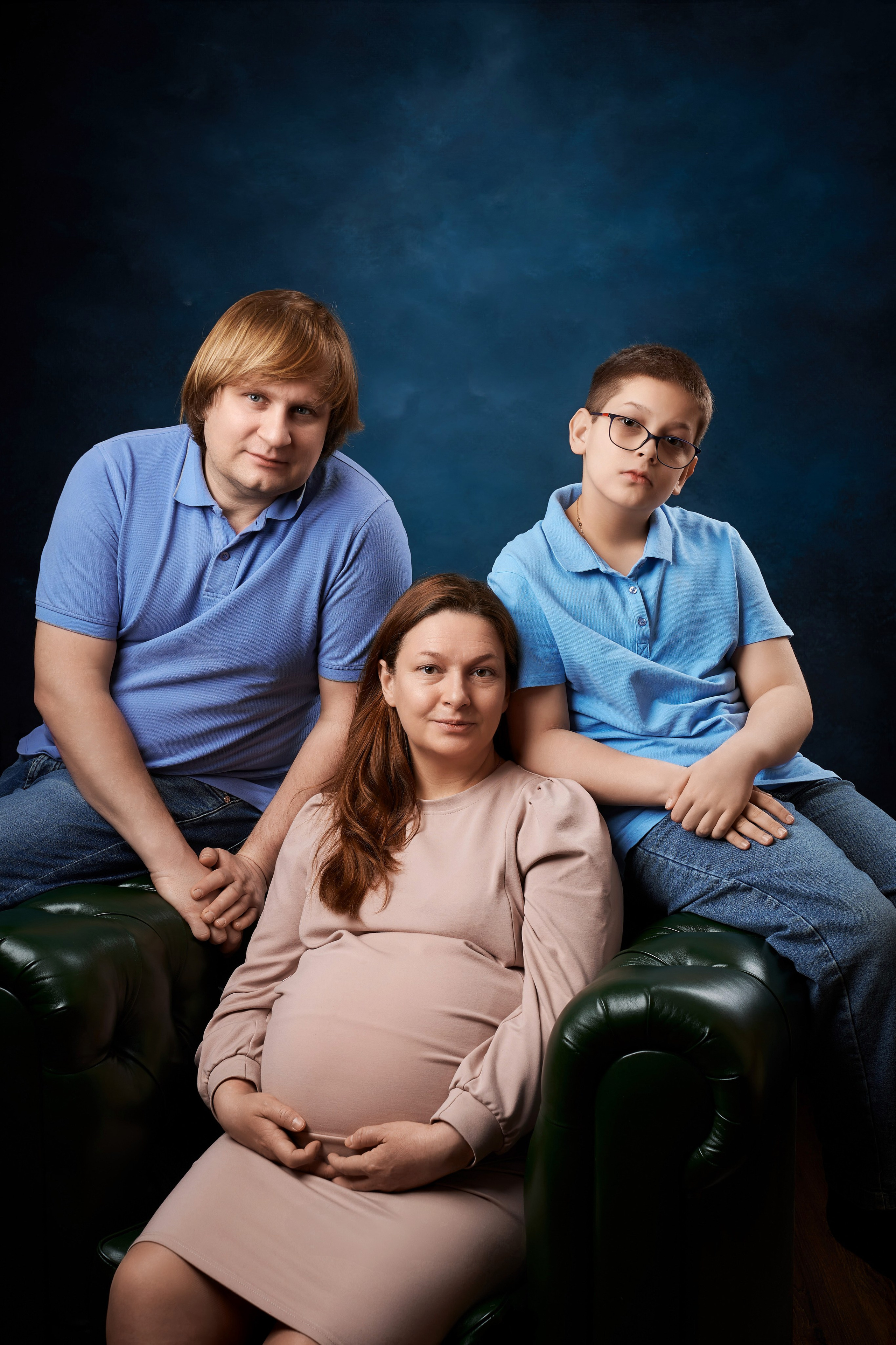 беременная мама с мужем и сыном в студии на семейной фотосессии 