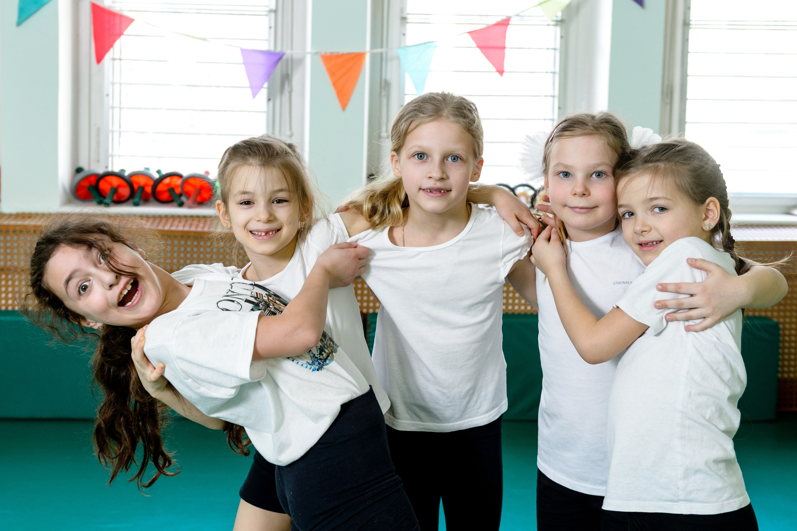 Группа девочек обнимаются в спортивном зале. 