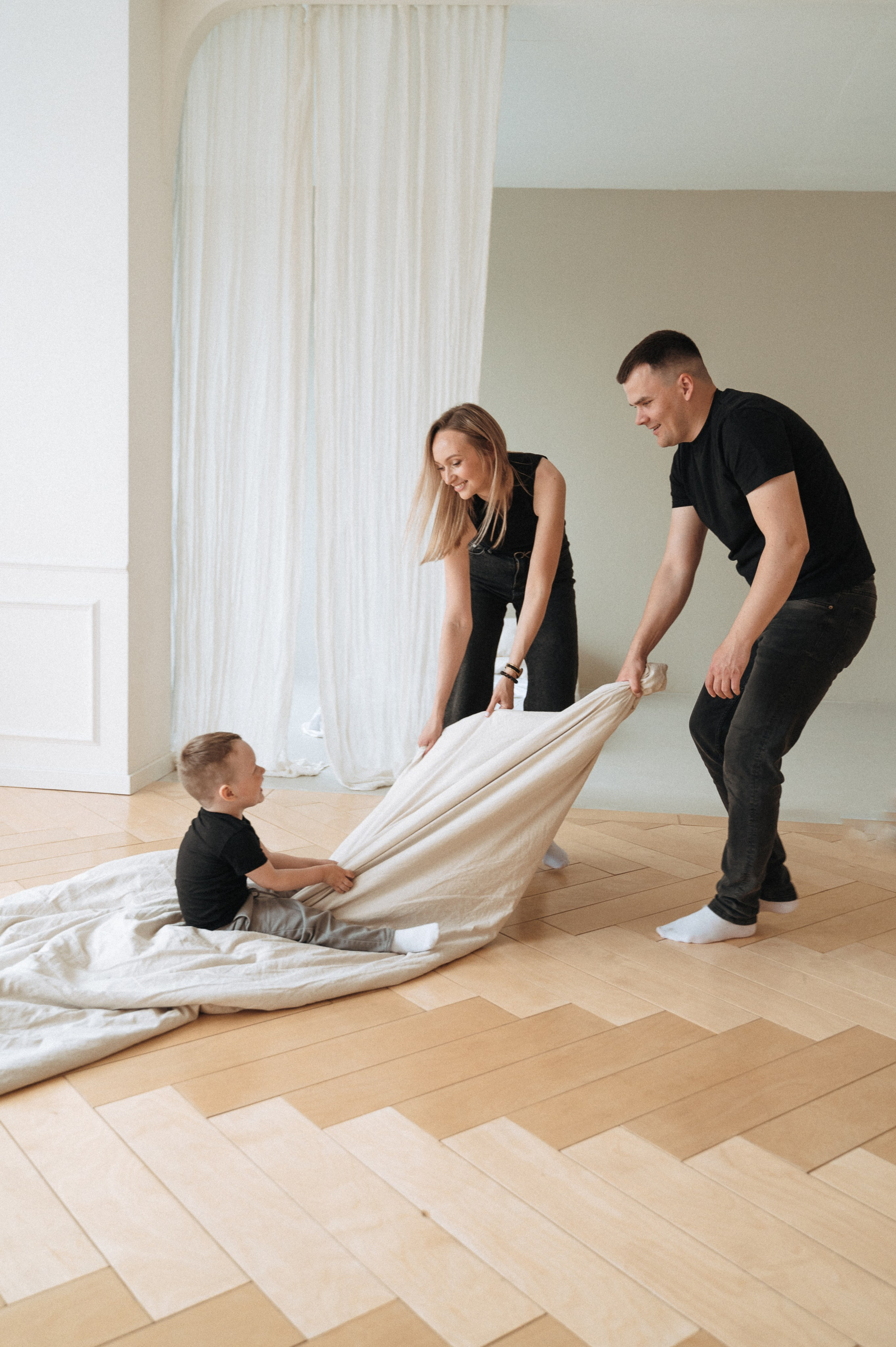 Родители катают мальчика на одеяле во время фотосессии