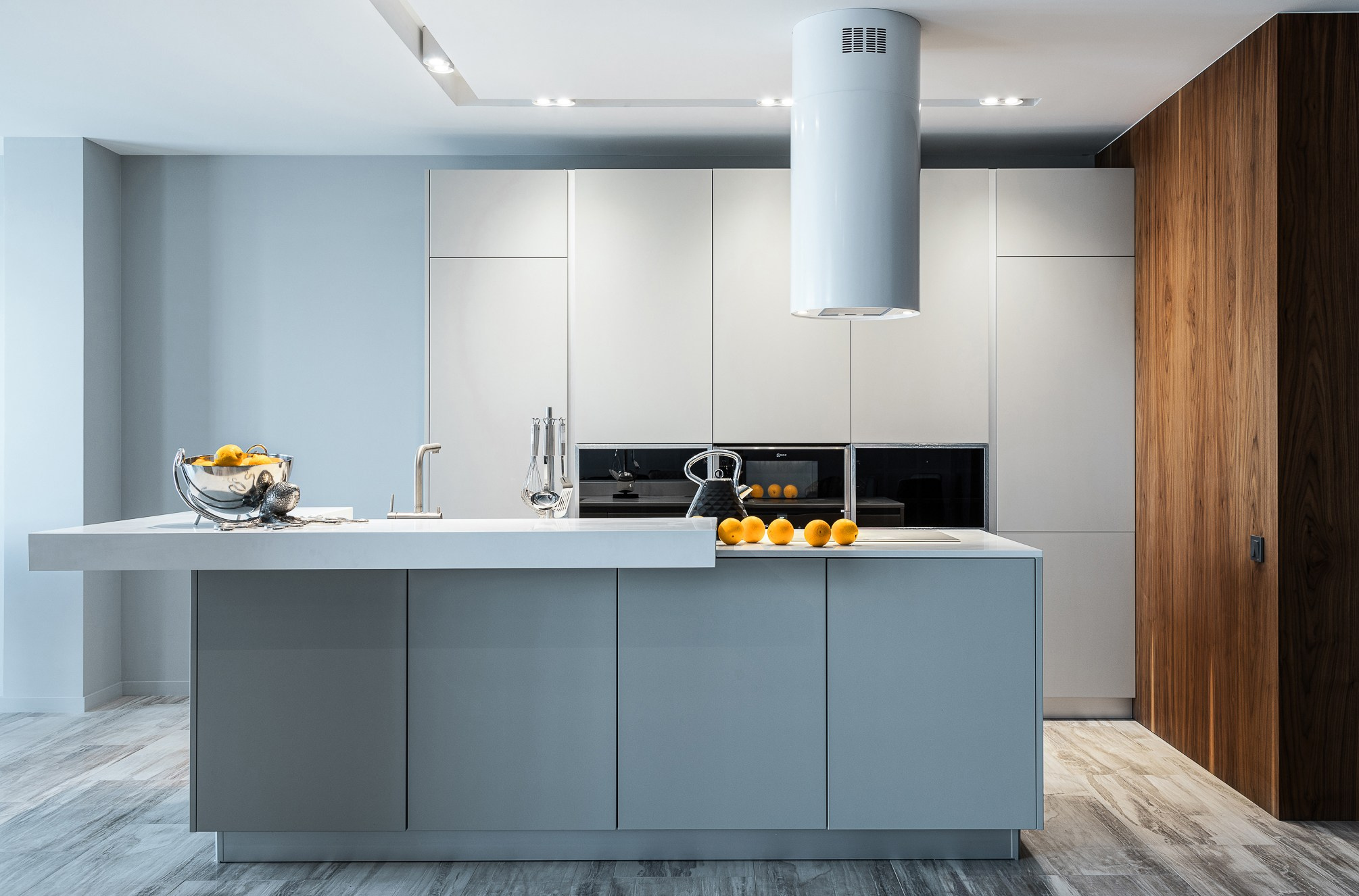 Апельсины на столе-острове посреди  светлой кухни.