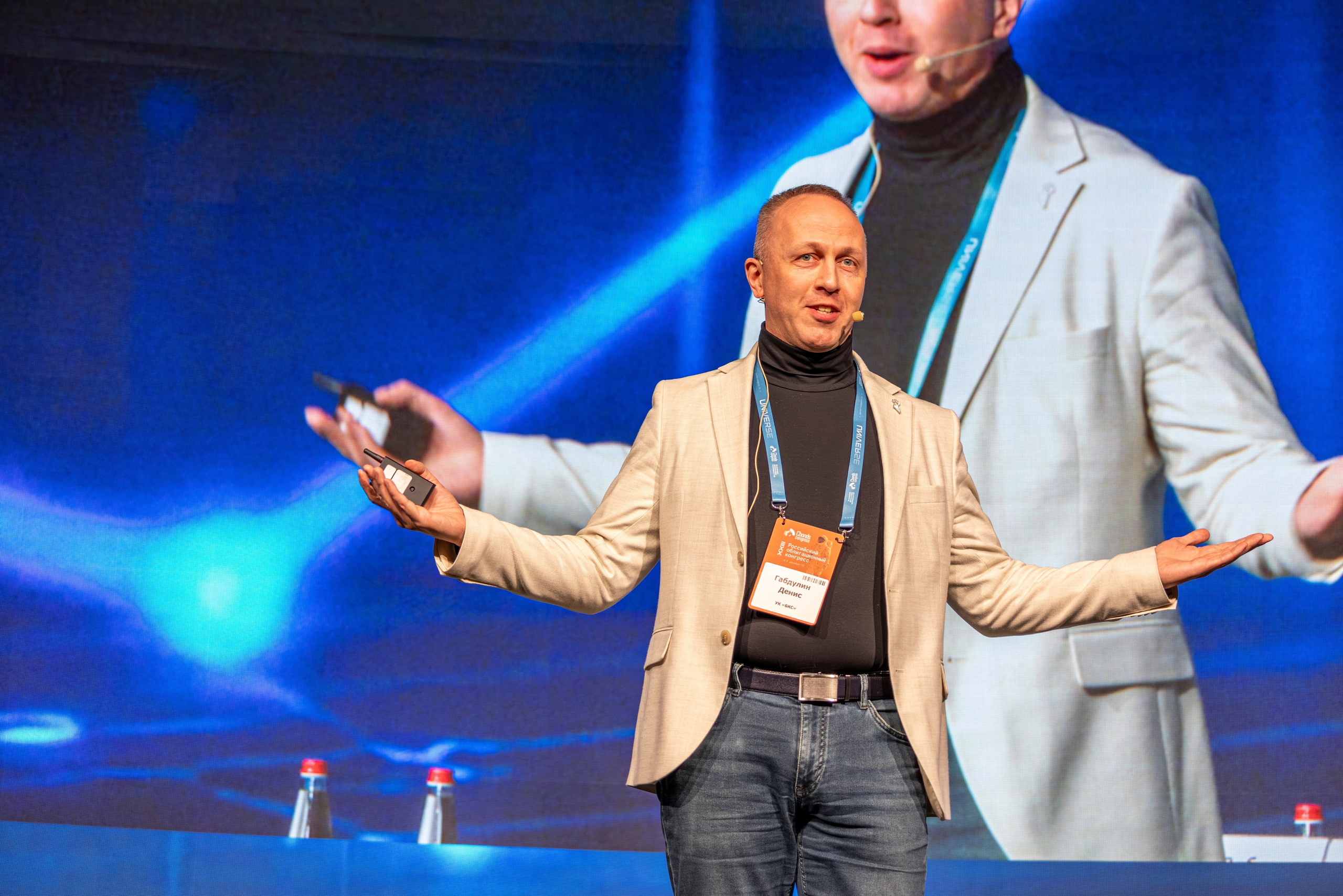 Спикер у трибуны активно жестикулирует во время выступления на облигационном конгрессе. 