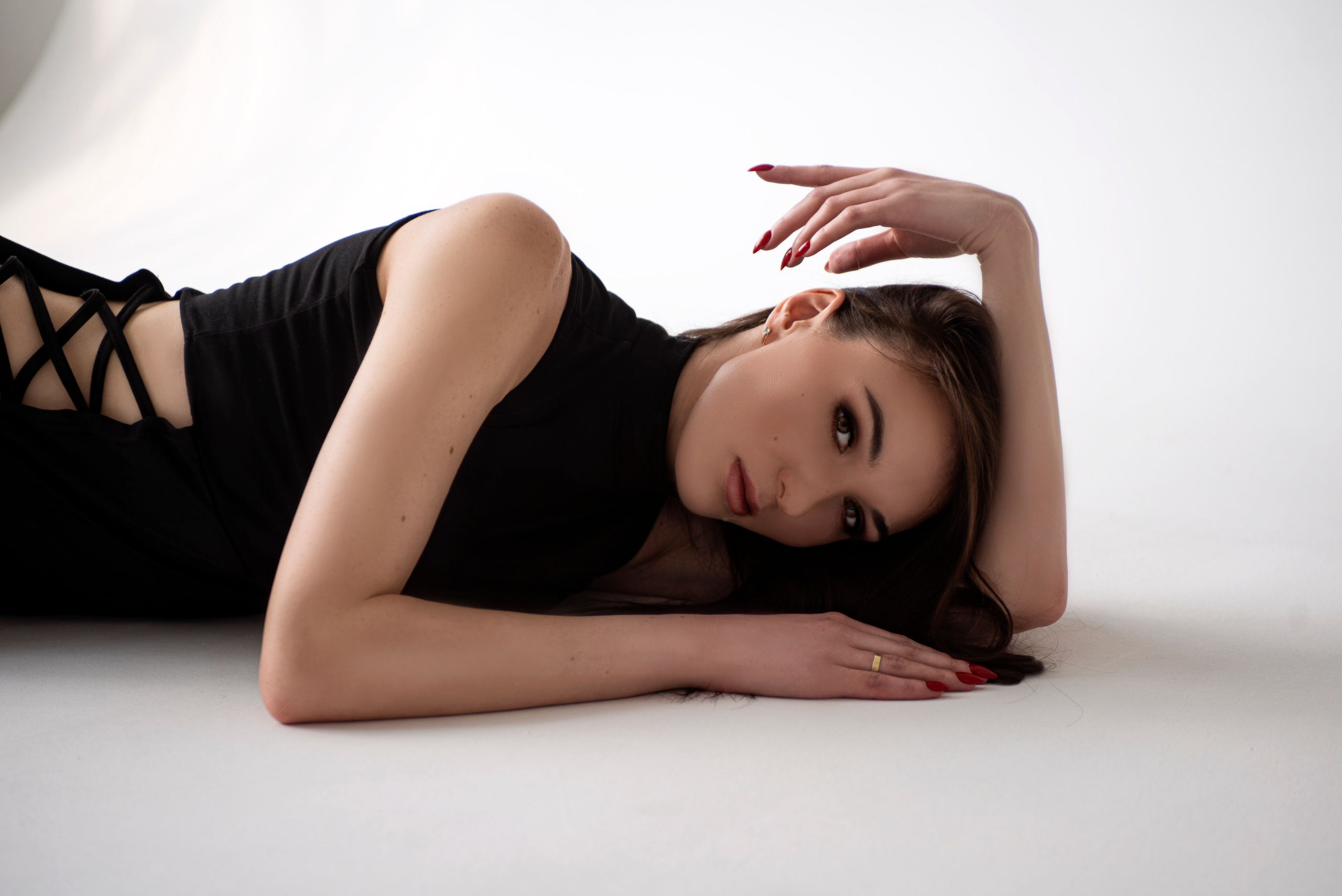 Горизонтальный портрет девушки, которая лежит на циклораме в фотостудии