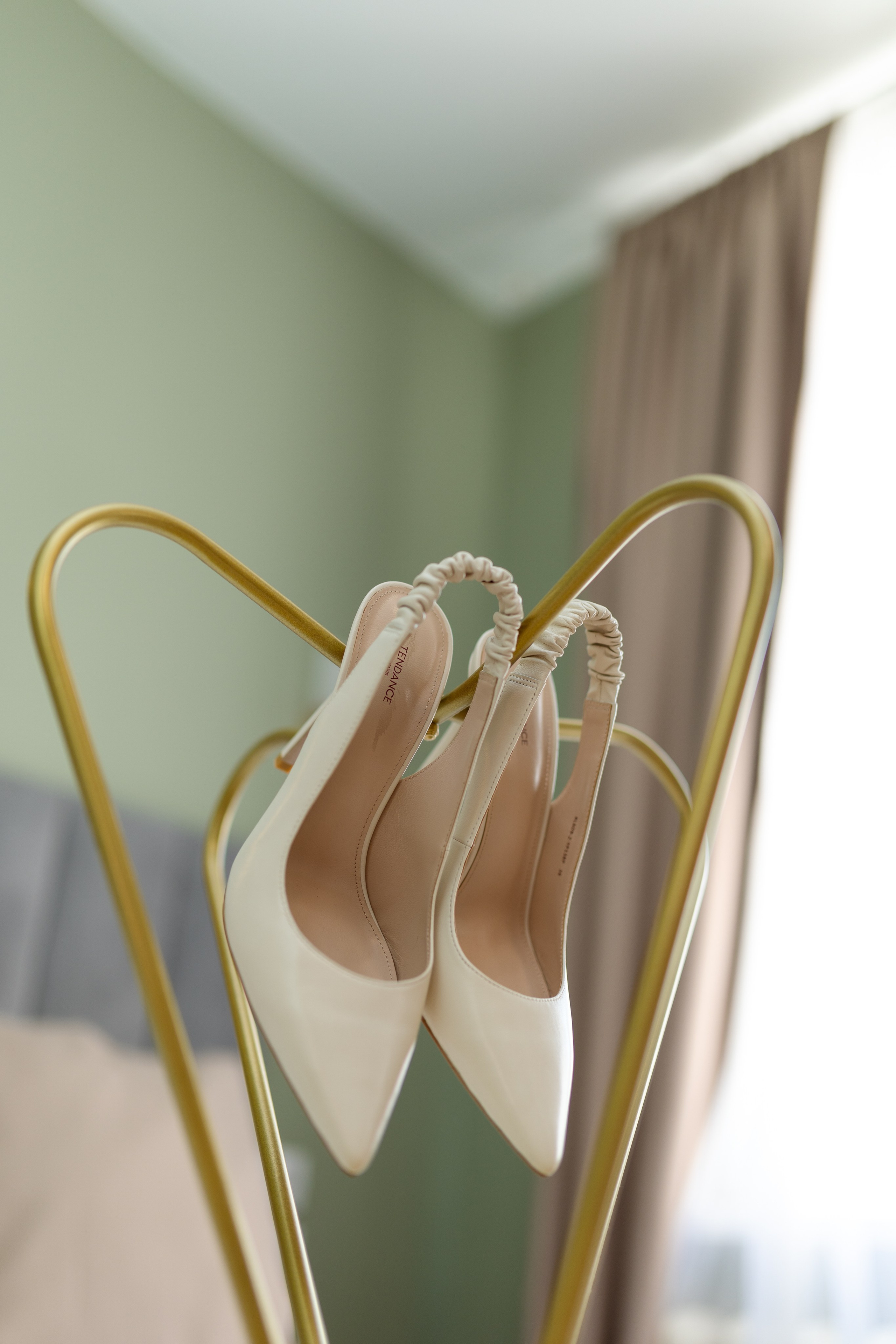 В углу на вешалке подвешены белые туфли.