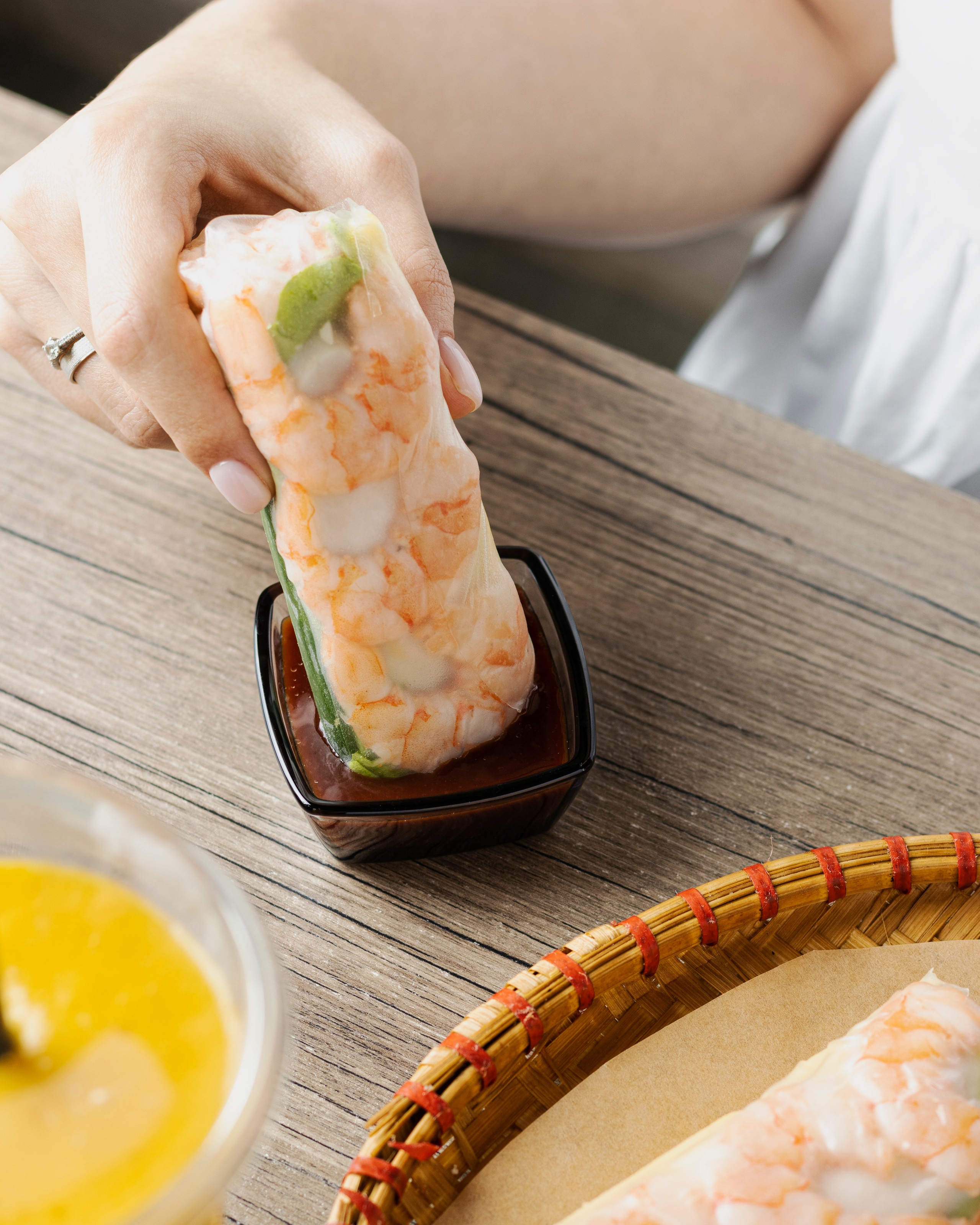 Спринг-ролл с креветками обмакивают в соус