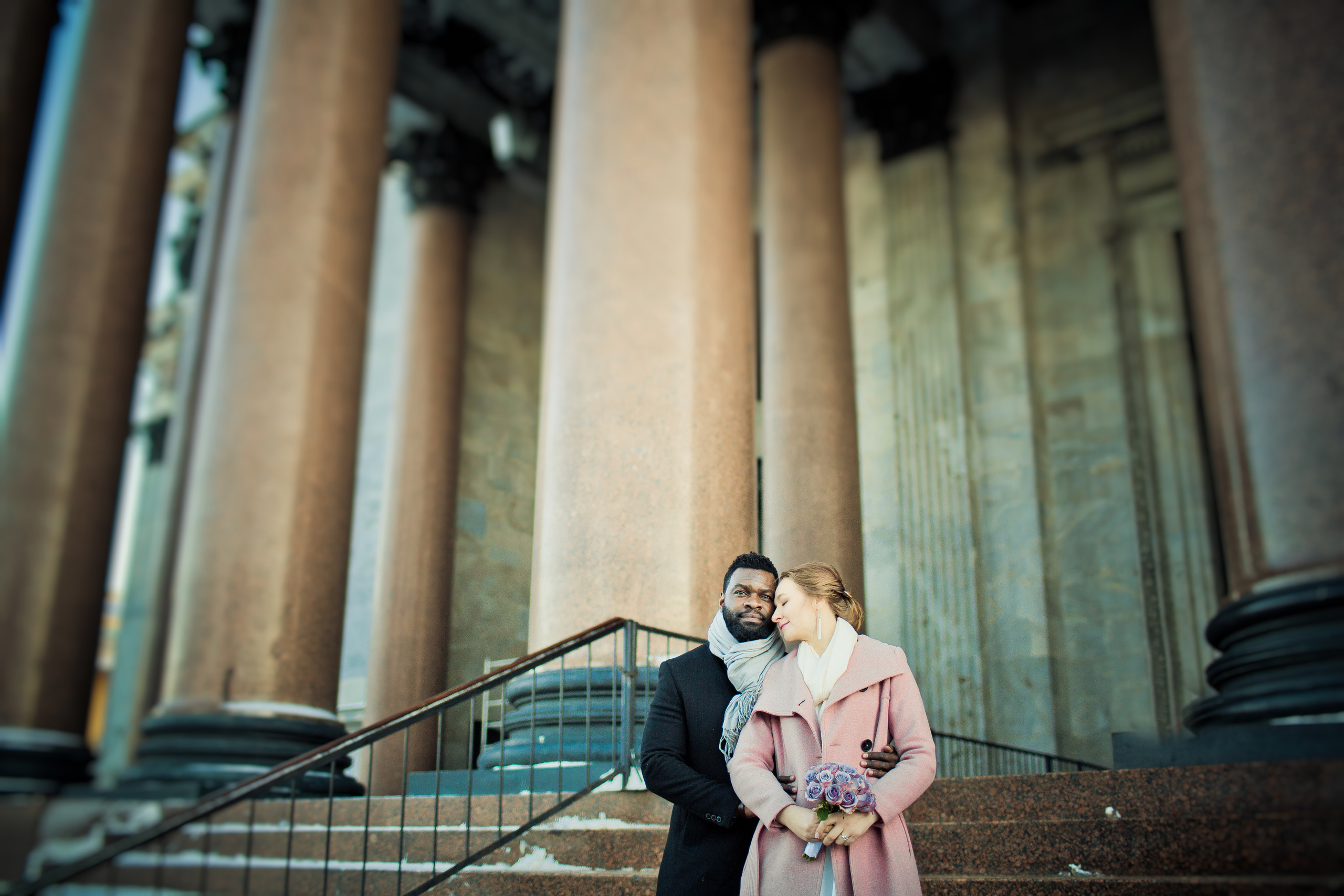 влюбленные в пальто с сиреневым букетом у колонн Исаакиевского собора