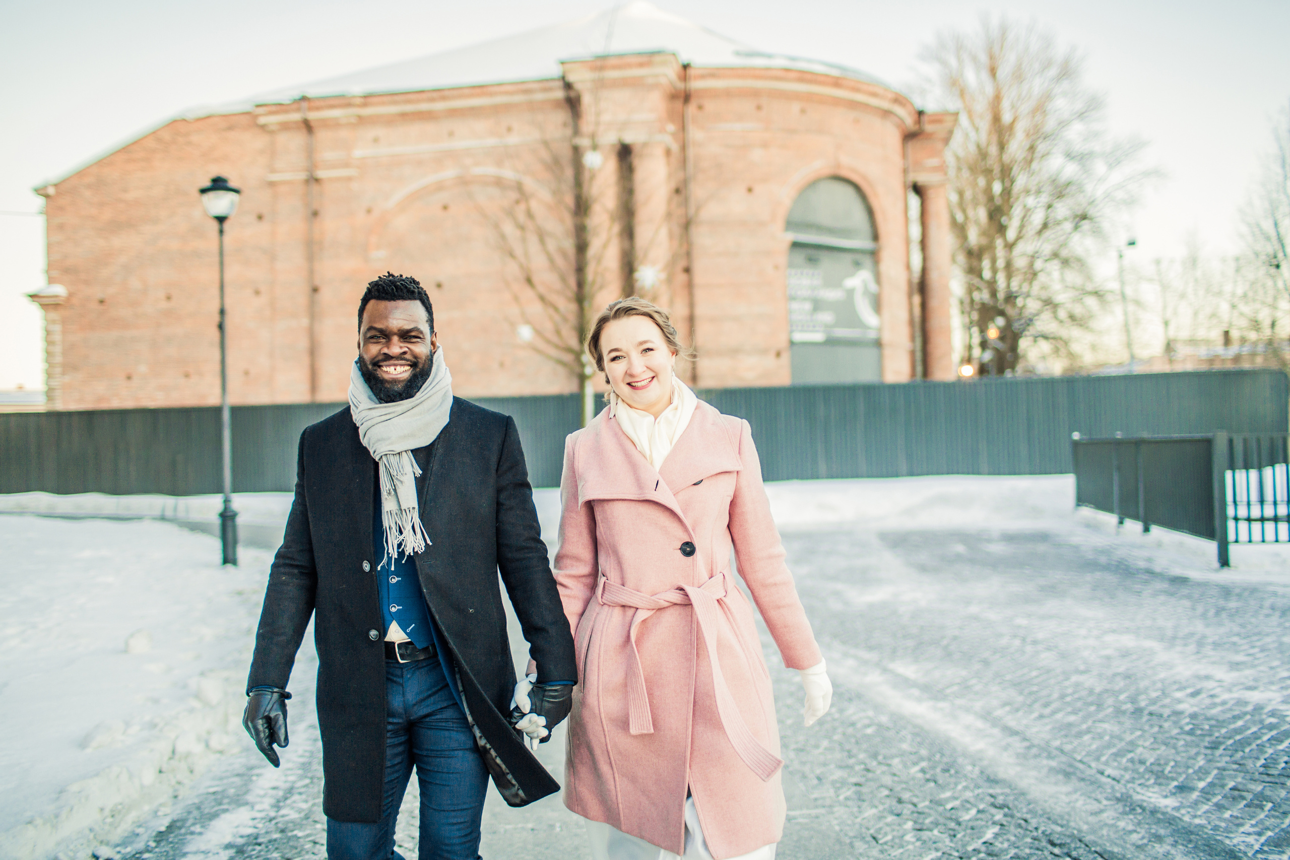 влюбленная интернациональная пара зимой идут взявшись за руки по мостовой Новой Голландии