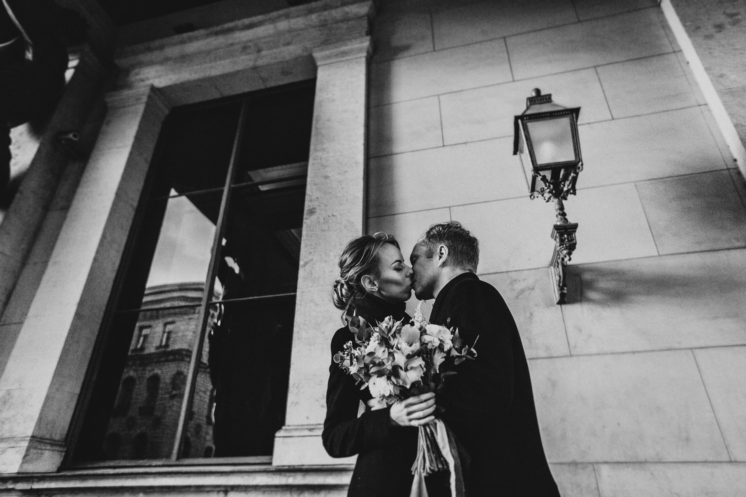 влюблённая пара с букетом целуется около фонаря