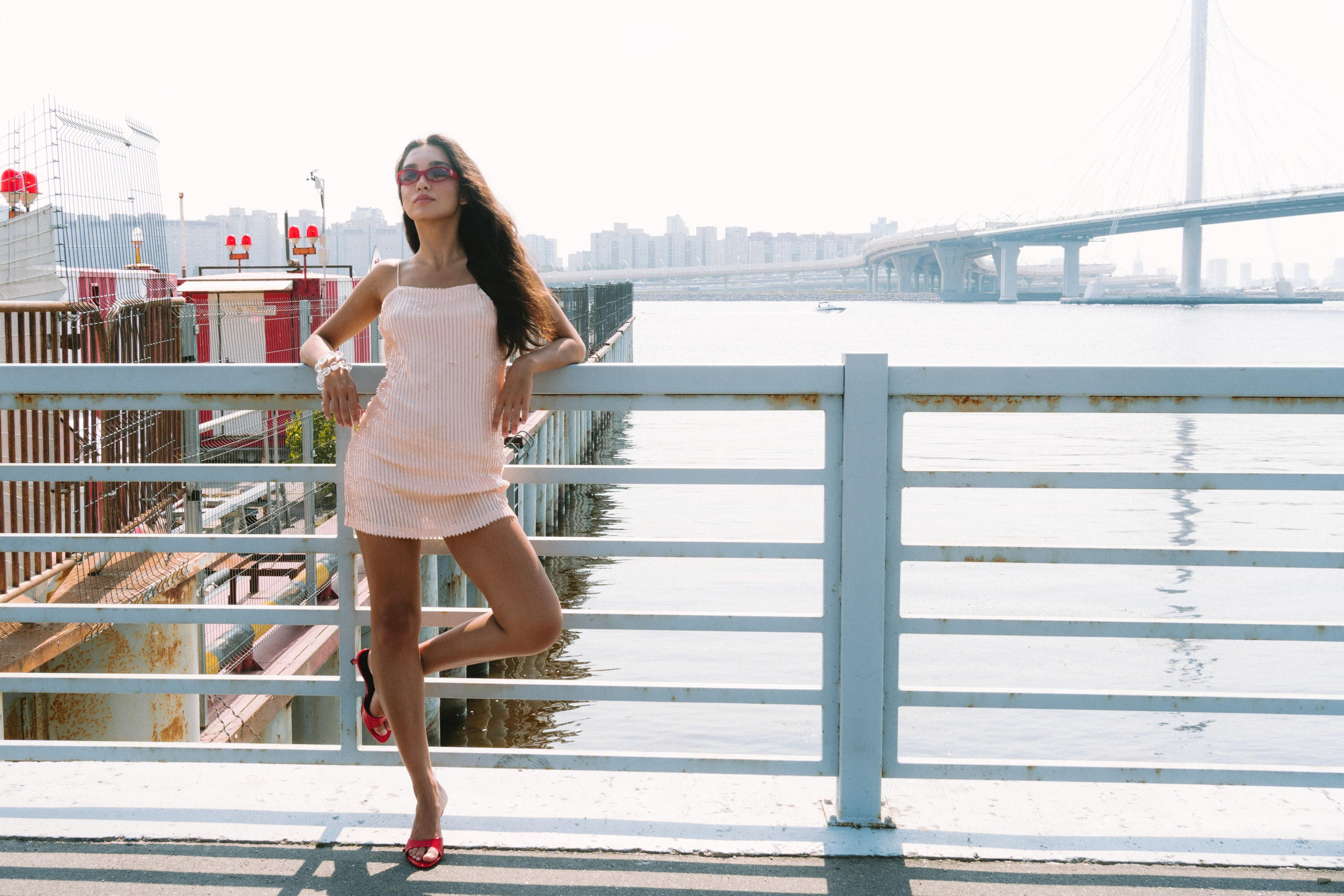 Модель в блестящем платье позирует на фоне залива в Питере