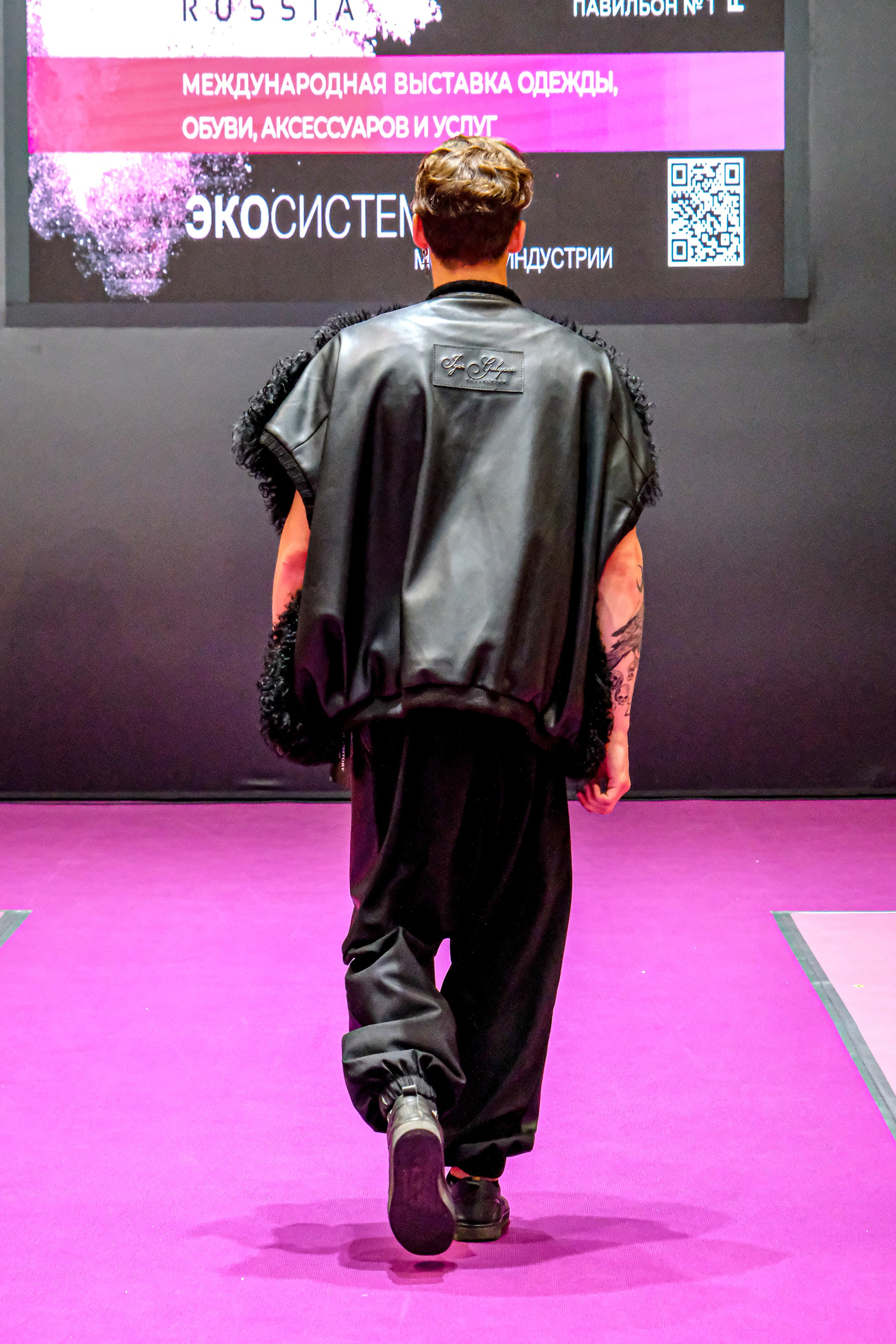  "Модели в ярких нарядах проходят по подиуму во время показа мод, освещенные яркими софитами и окруженные восторженными зрителями."