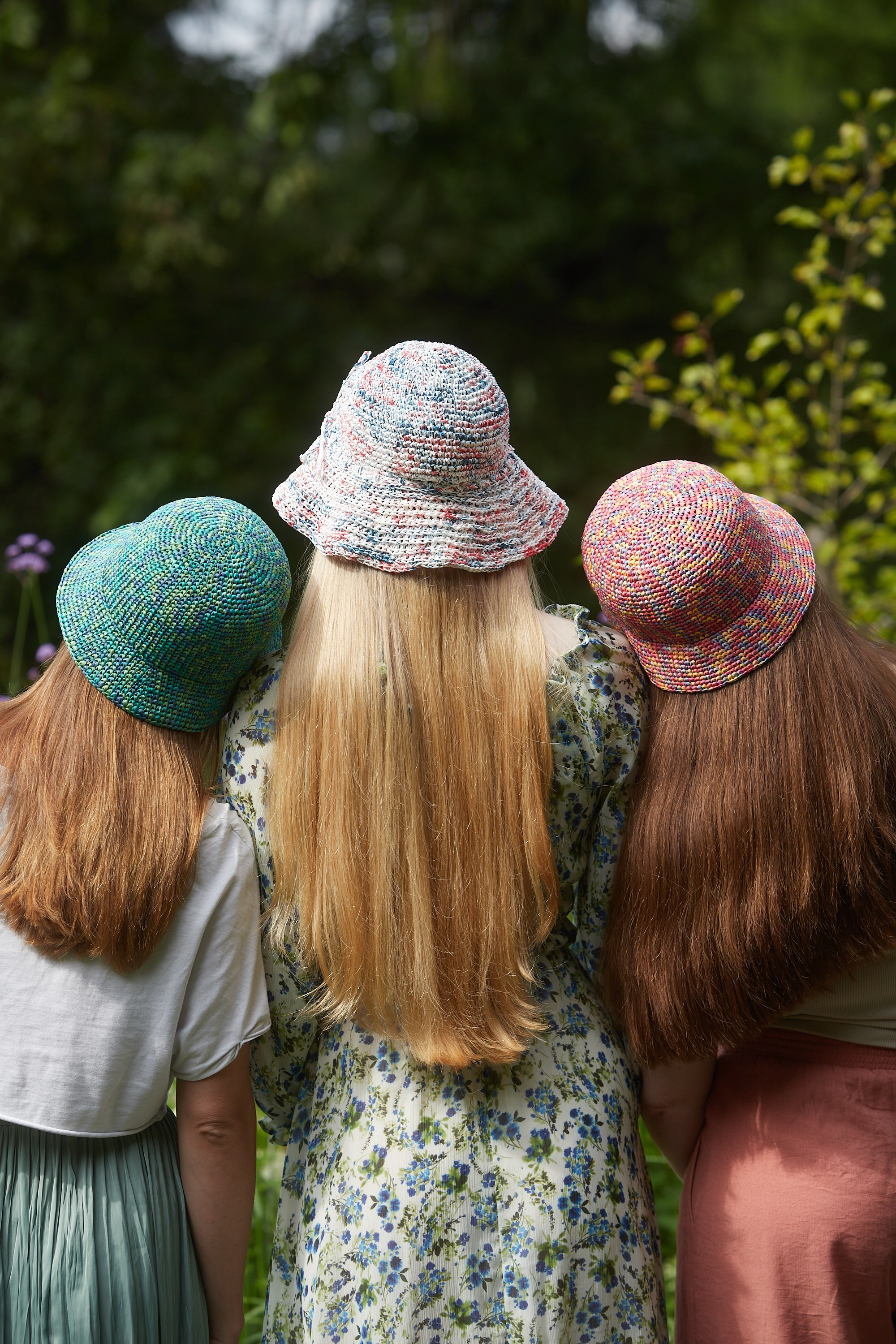 Предметная съёмка оранжевой вязаной сумки на фоне зелени.