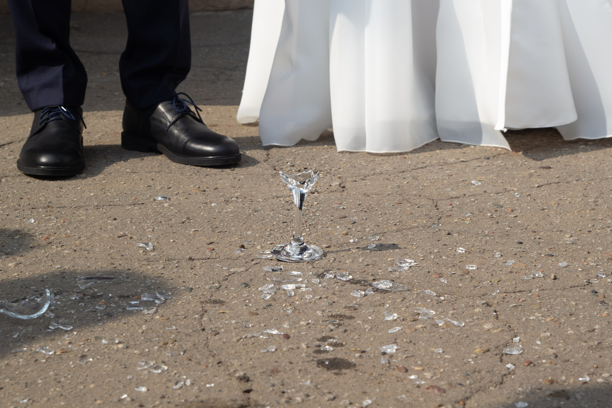 Осколки разбившегося бокала на асфальте перед ногами жениха и невесты — свадебная традиция на удачу.