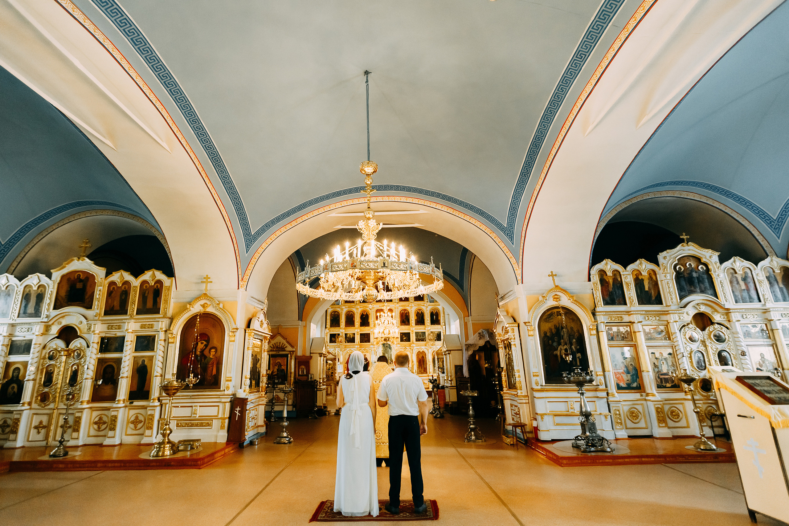 Жених и невеста, держа в руках зажженные свечи, изображающие духовный свет таинства, торжественно входят на середину храма.