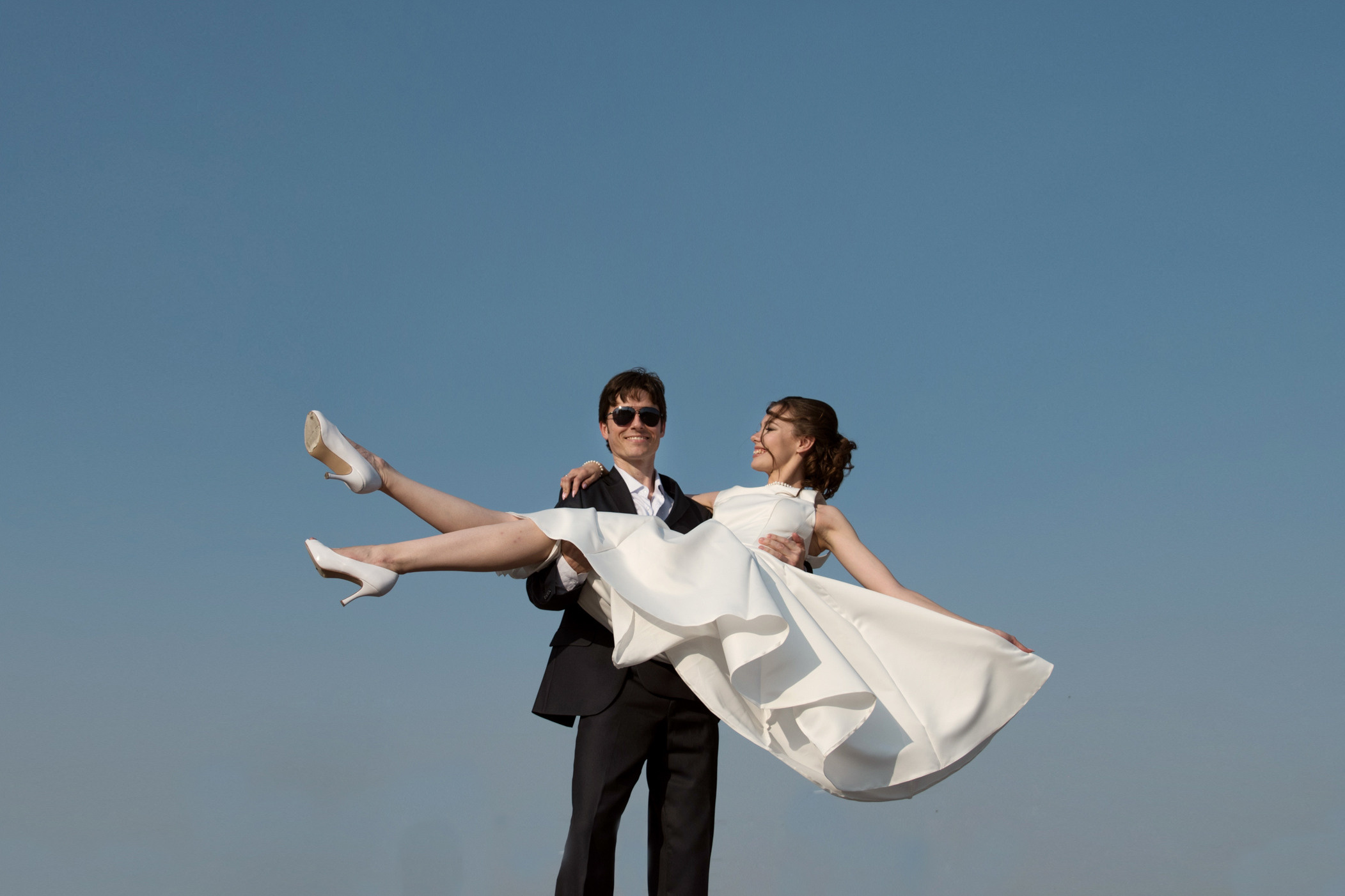 счастливые молодожены на фоне синего неба